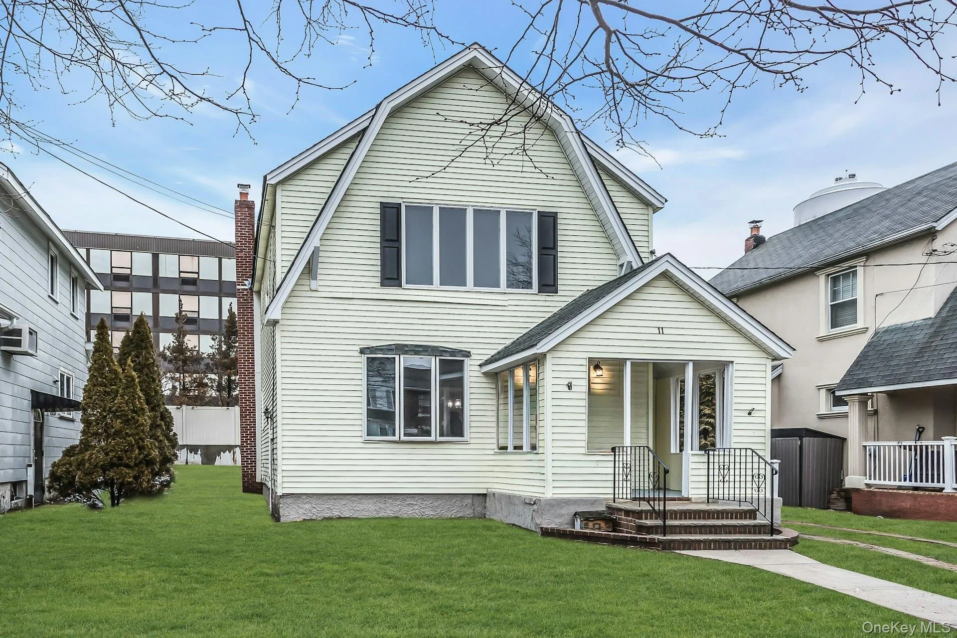 Gabled-roof residence featuring light-colored siding, a covered porch entry, and a prominent second-story window array Gabled-roof residence featuring light-colored siding, a covered porch entry, and a prominent second-story window array