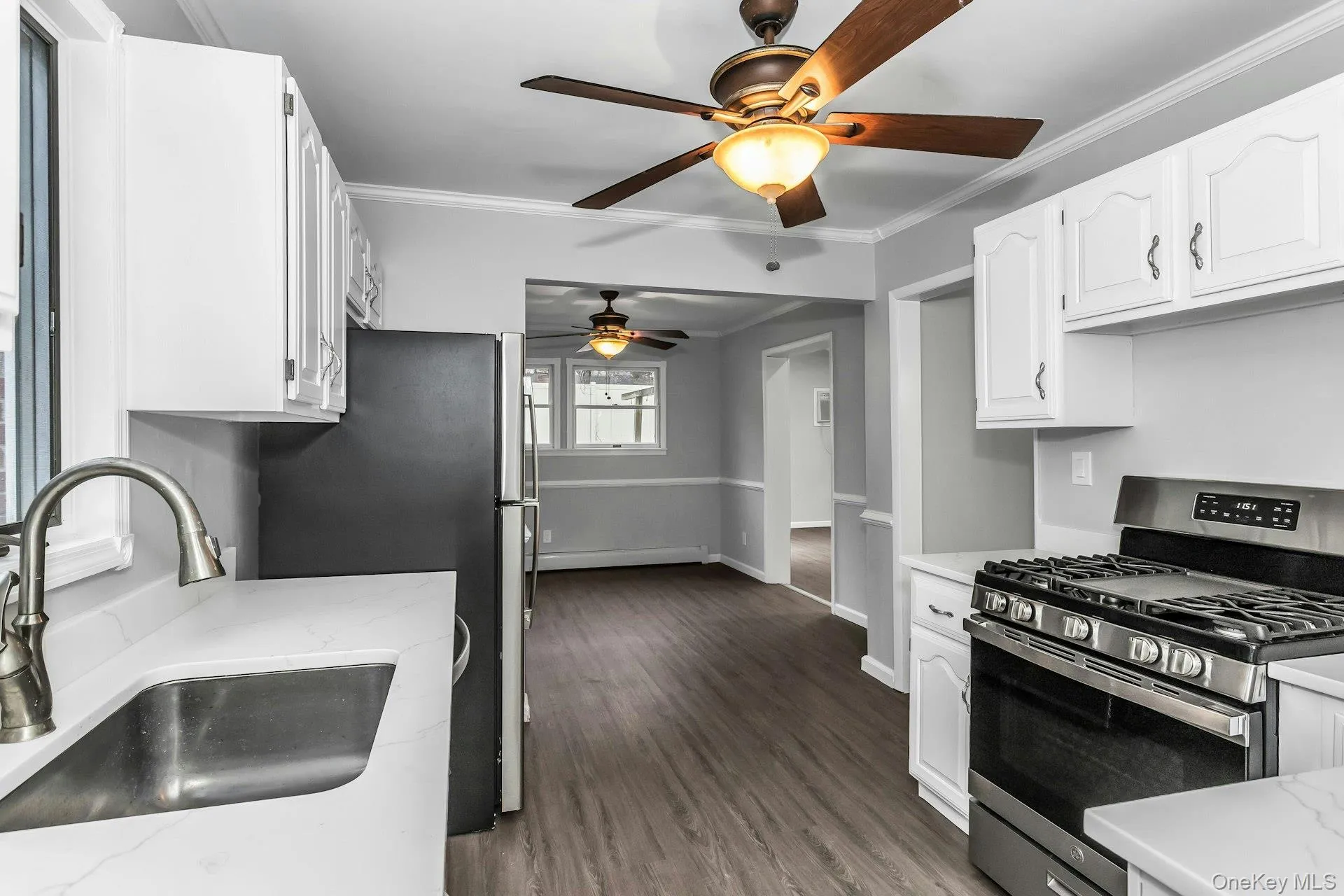 Kitchen featuring white cabinetry, light countertops, wood-finish flooring, and a stainless steel range Kitchen featuring white cabinetry, light countertops, wood-finish flooring, and a stainless steel range