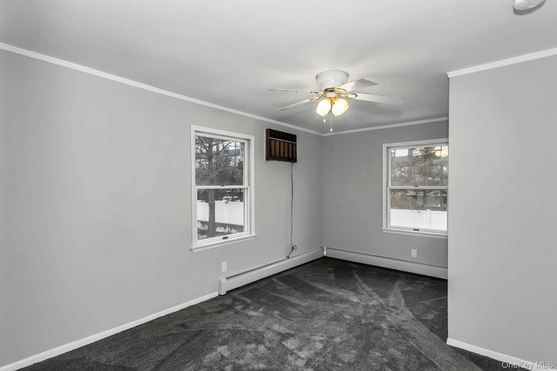 Spacious room featuring light gray walls, dark gray carpeting, and white trim Spacious room featuring light gray walls, dark gray carpeting, and white trim