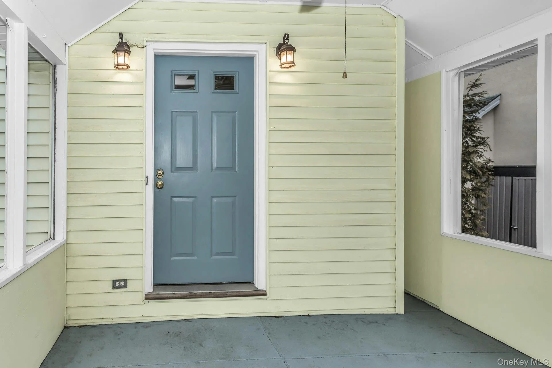 Enclosed porch entry featuring a paneled door with upper glass inserts, two exterior wall lanterns, and a ceiling fan Enclosed porch entry featuring a paneled door with upper glass inserts, two exterior wall lanterns, and a ceiling fan