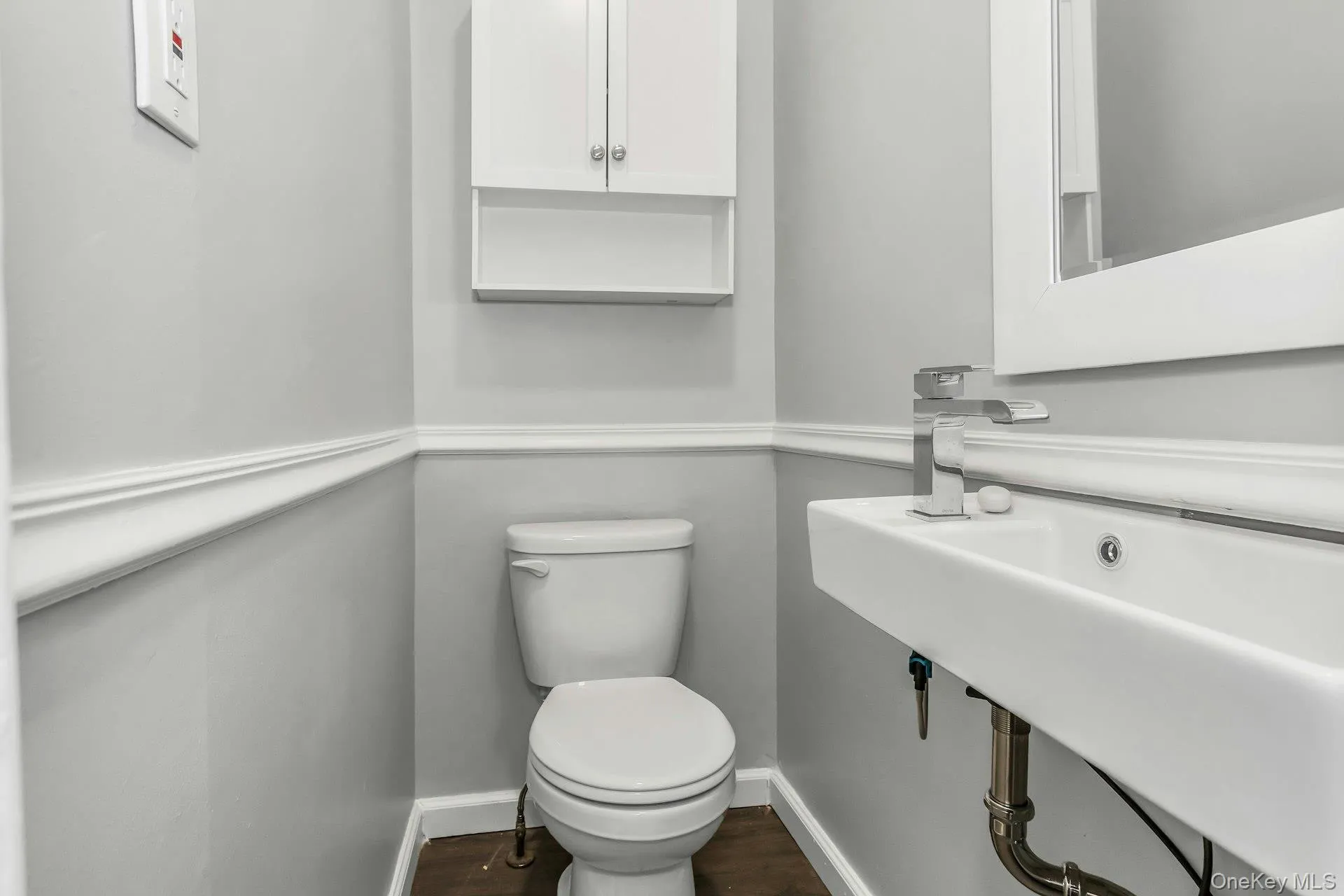 Bathroom featuring a wall-mounted floating sink, chrome faucet, and white wall cabinetry Bathroom featuring a wall-mounted floating sink, chrome faucet, and white wall cabinetry