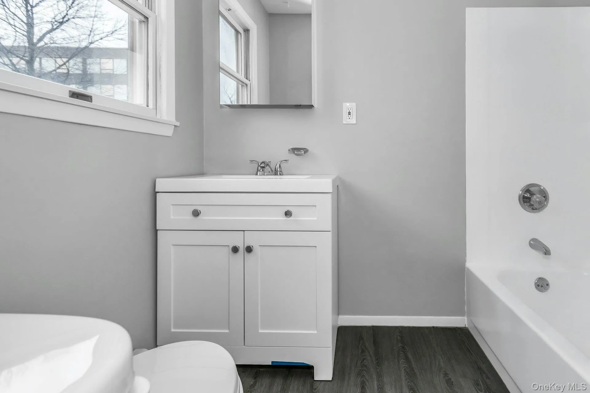 Bathroom featuring a white vanity with integrated sink, chrome faucet, and mirrored medicine cabinet Bathroom featuring a white vanity with integrated sink, chrome faucet, and mirrored medicine cabinet