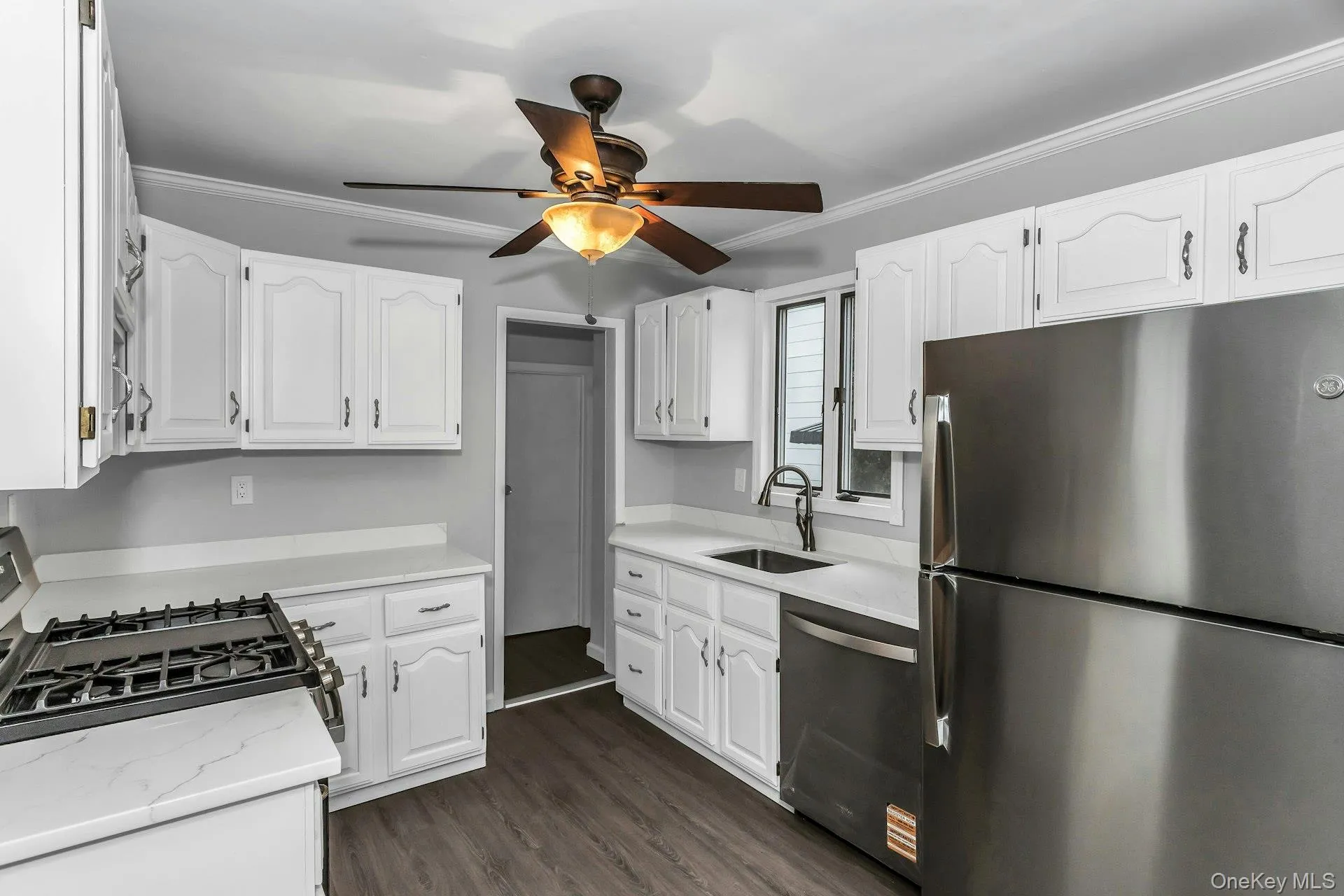 Kitchen featuring white cabinetry, light countertops, wood-finish flooring, stainless steel appliances, and a gas range Kitchen featuring white cabinetry, light countertops, wood-finish flooring, stainless steel appliances, and a gas range