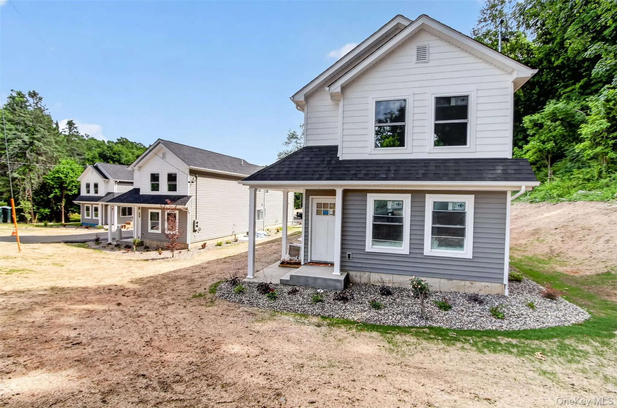 Two-story residence featuring white and gray siding, a covered front porch, and a dark shingle roof Two-story residence featuring white and gray siding, a covered front porch, and a dark shingle roof