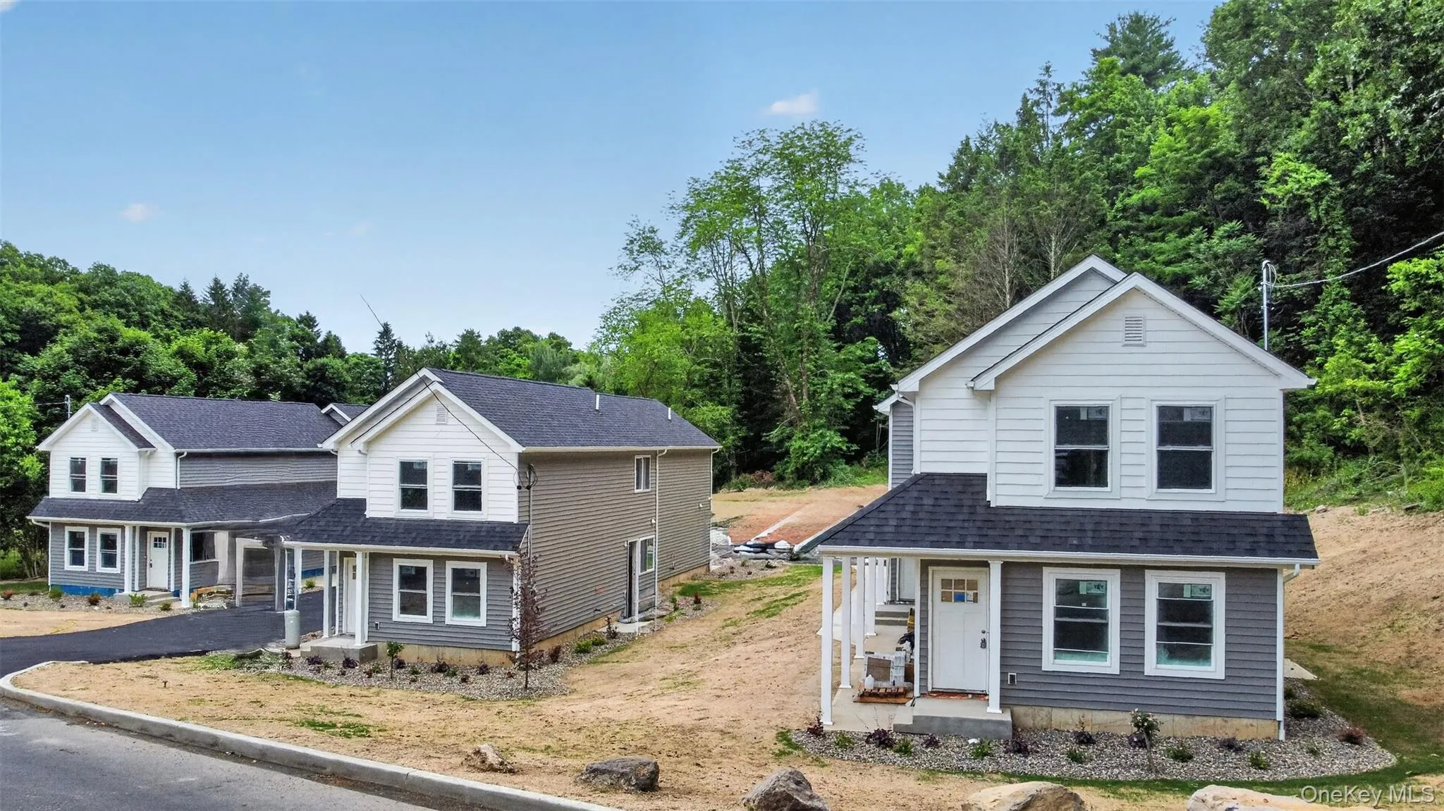 Newly constructed two-story residence featuring a covered front porch, white trim, and a dark shingle roof Newly constructed two-story residence featuring a covered front porch, white trim, and a dark shingle roof