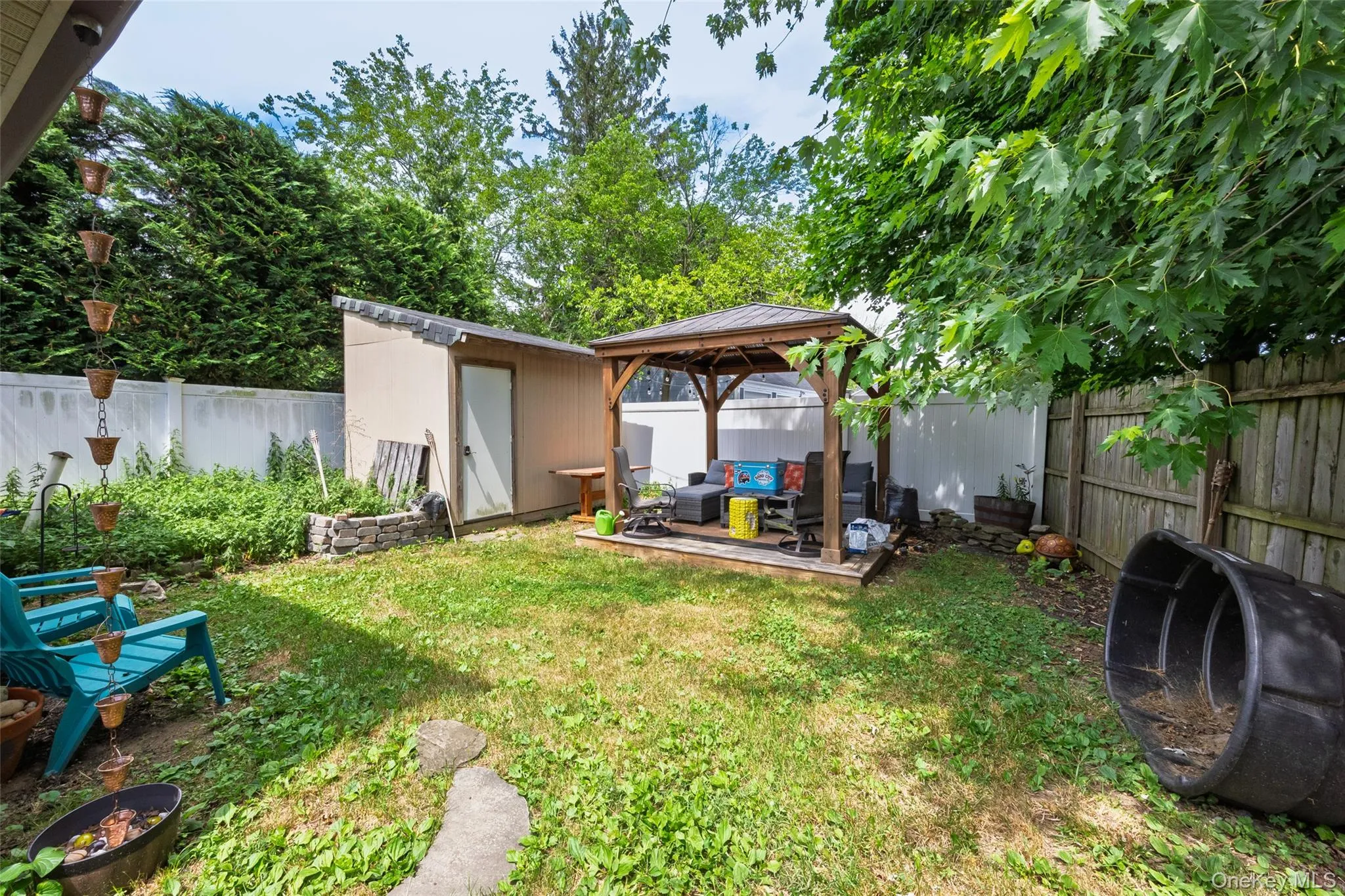 Expansive backyard featuring a covered gazebo on a wooden deck, a storage shed, and a privacy fence Expansive backyard featuring a covered gazebo on a wooden deck, a storage shed, and a privacy fence