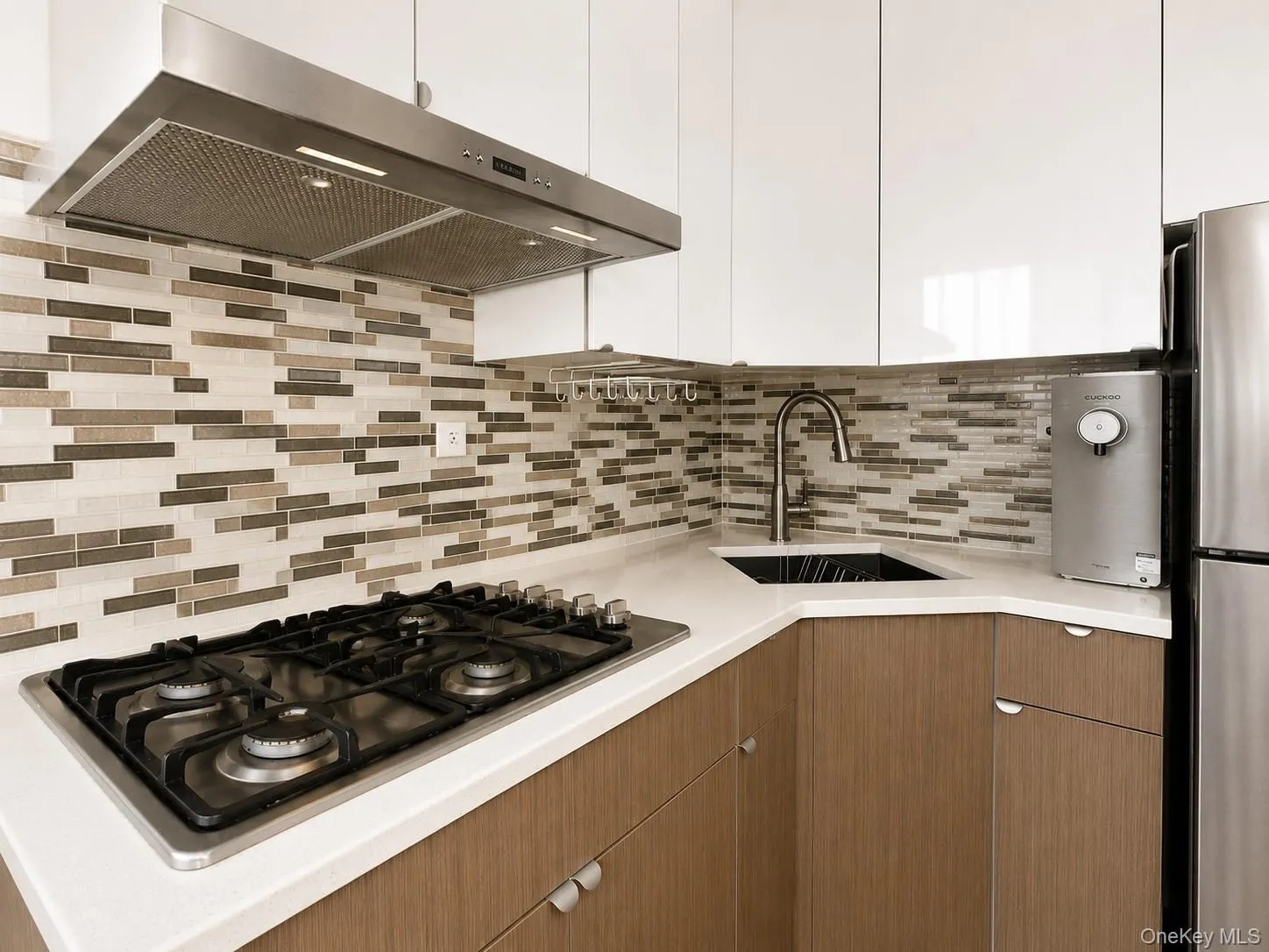 Modern kitchen featuring white upper cabinetry, wood-finish lower cabinetry, and light-toned countertops Modern kitchen featuring white upper cabinetry, wood-finish lower cabinetry, and light-toned countertops