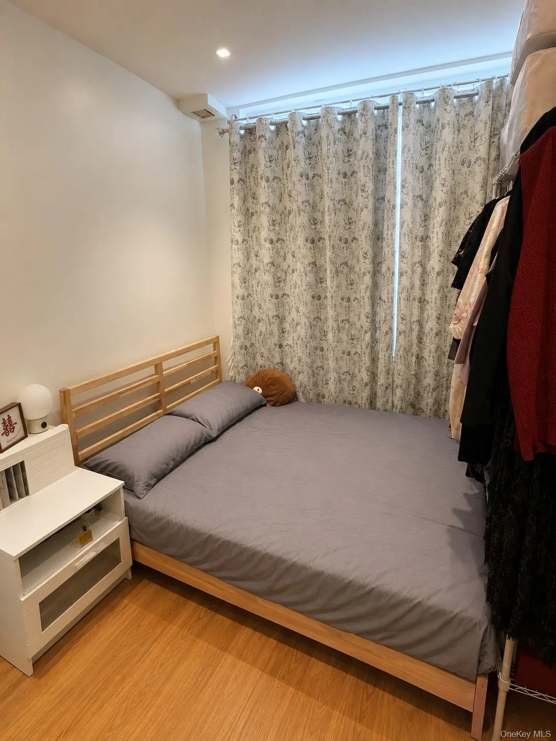 Compact bedroom featuring wood-finish flooring, a full-height window with curtain rod, recessed ceiling lighting, and a neutral wall finish Compact bedroom featuring wood-finish flooring, a full-height window with curtain rod, recessed ceiling lighting, and a neutral wall finish