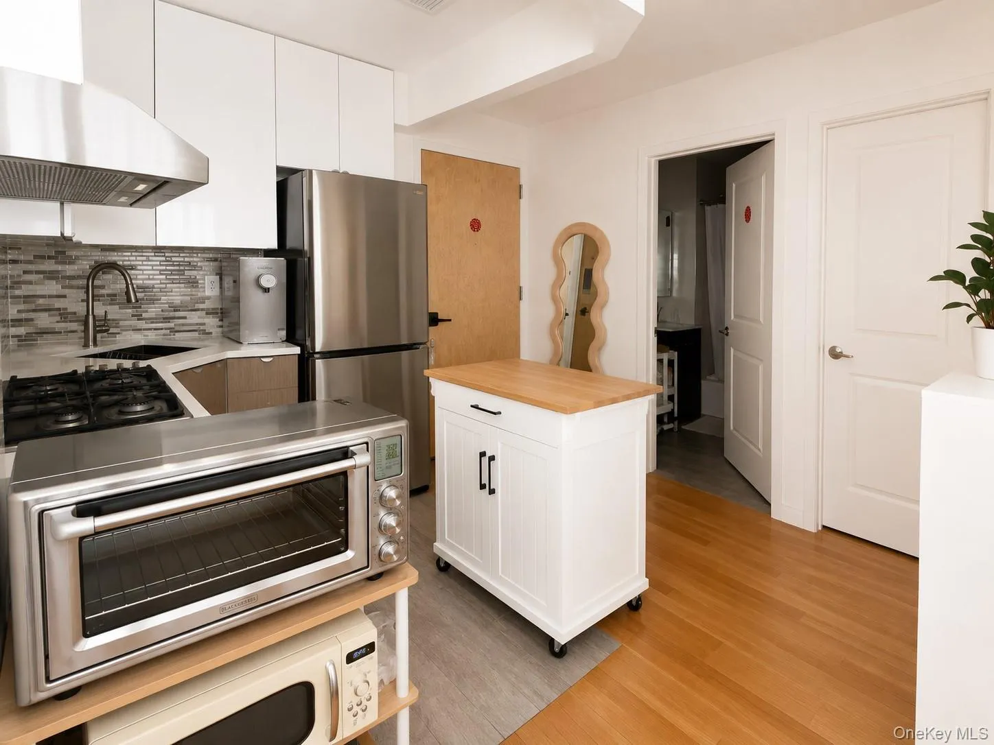 Compact kitchen featuring stainless steel appliances, a gas range, and a mosaic tile backsplash Compact kitchen featuring stainless steel appliances, a gas range, and a mosaic tile backsplash