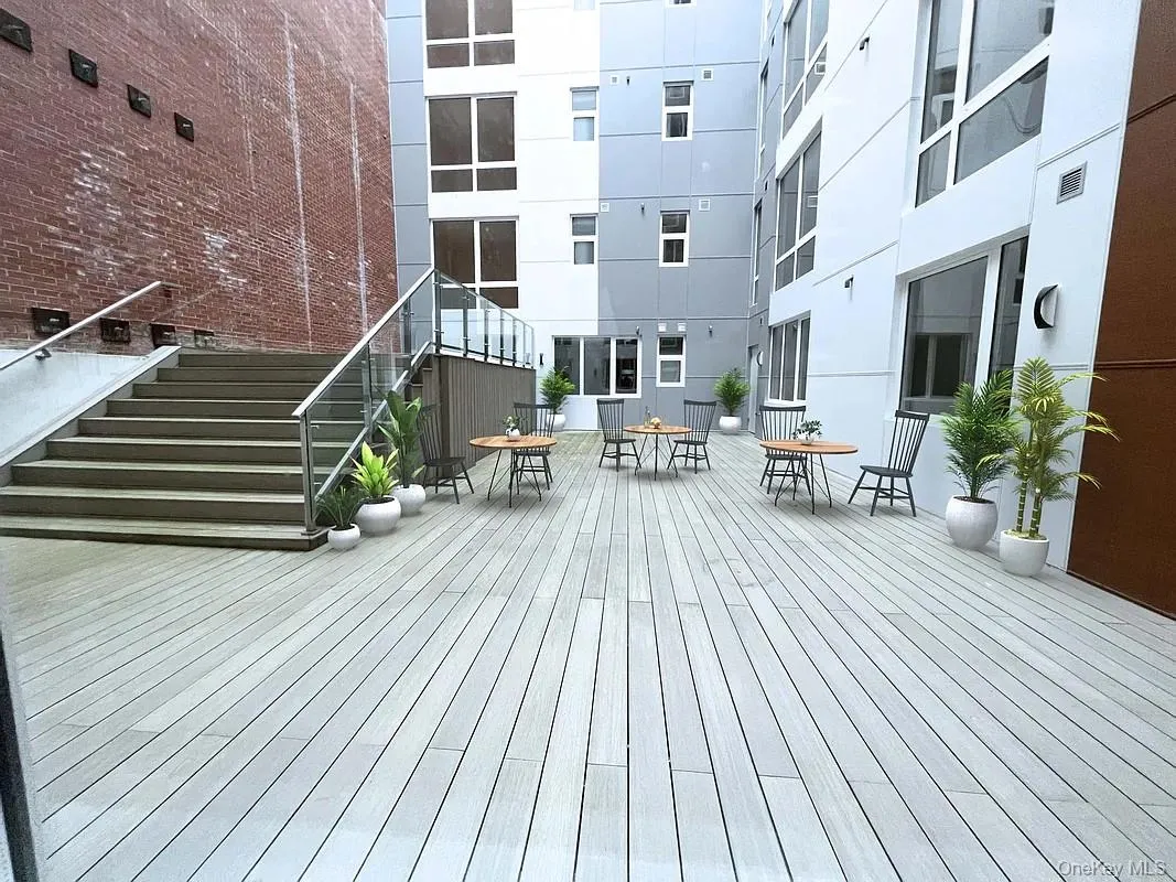 Expansive light wood-finish deck with built-in stairs featuring stainless steel and glass railings Expansive light wood-finish deck with built-in stairs featuring stainless steel and glass railings