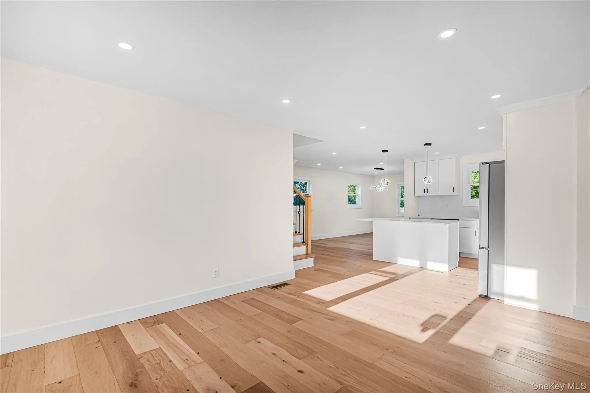 Light wood-finish flooring extending into an open-concept area with recessed lighting Light wood-finish flooring extending into an open-concept area with recessed lighting