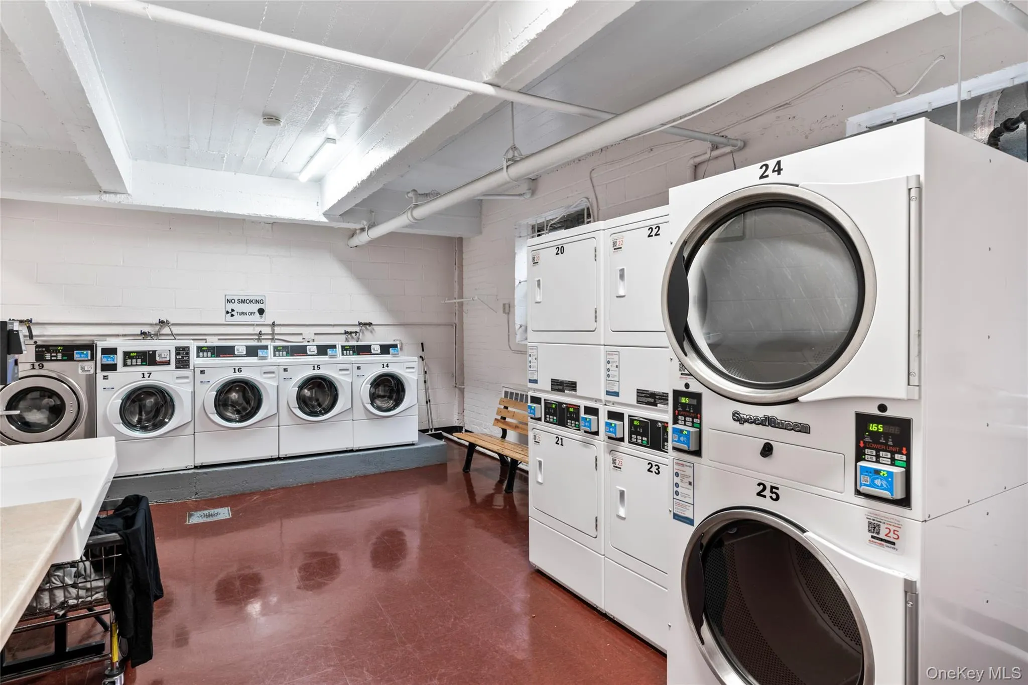 Community laundry featuring stacked washer / drying machine, independent washer and dryer, and concrete block wall Community laundry featuring stacked washer / drying machine, independent washer and dryer, and concrete block wall