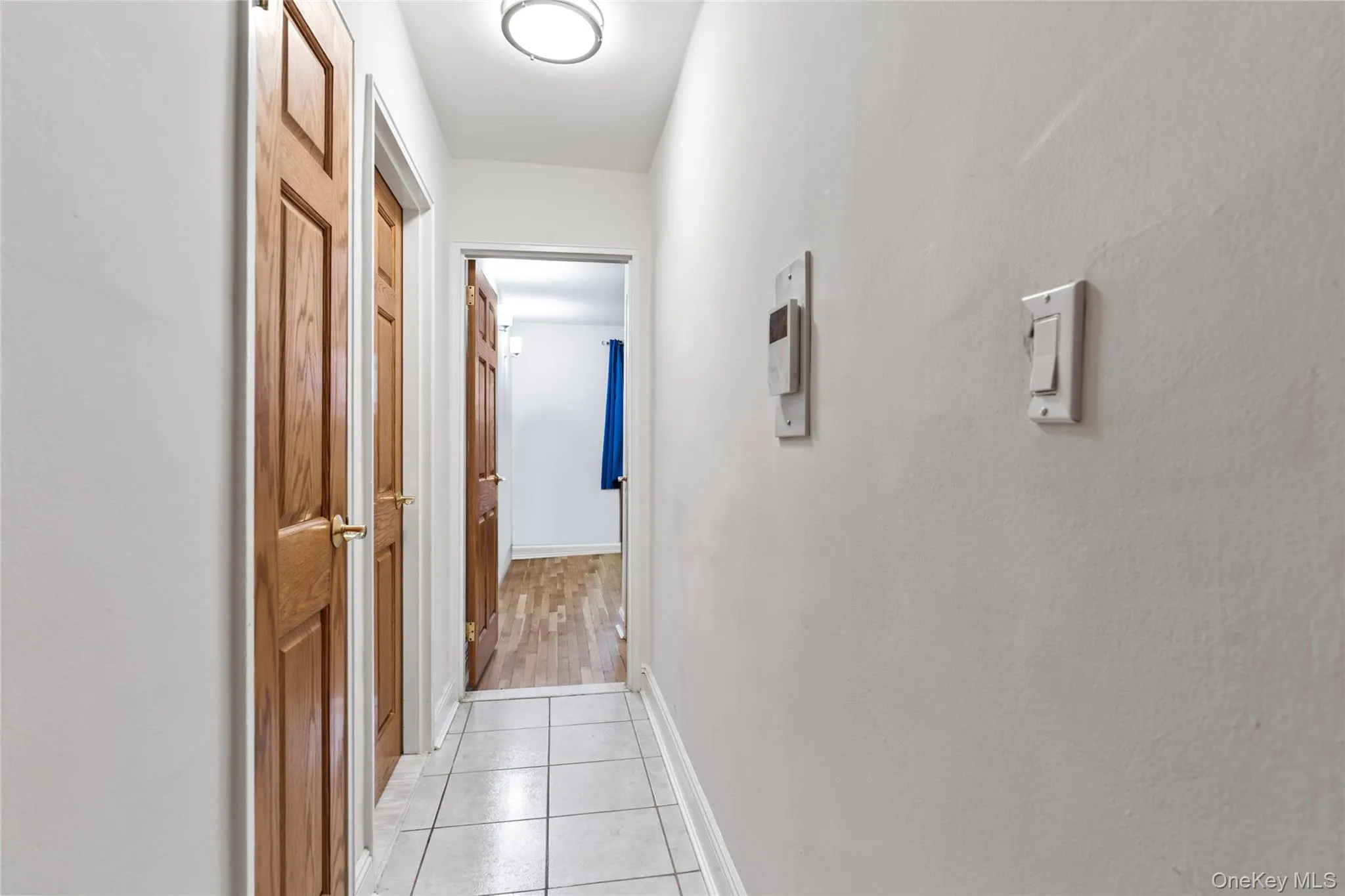 Hall with light tile patterned floors and baseboards Hall with light tile patterned floors and baseboards