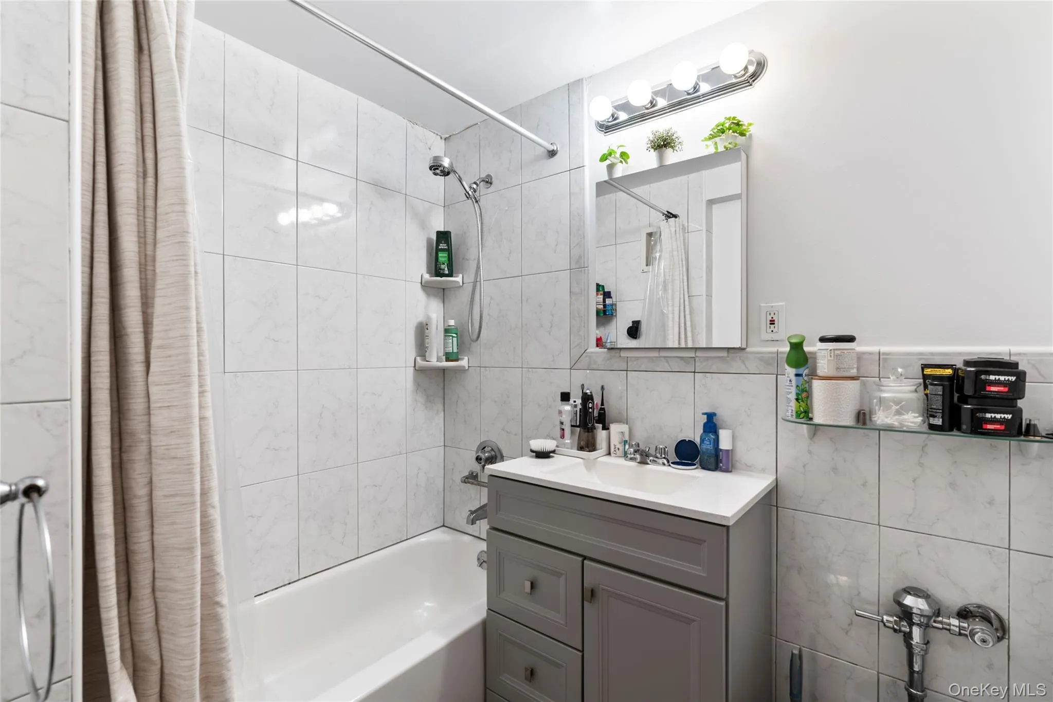 Bathroom featuring shower / tub combo, vanity, and tile walls Bathroom featuring shower / tub combo, vanity, and tile walls