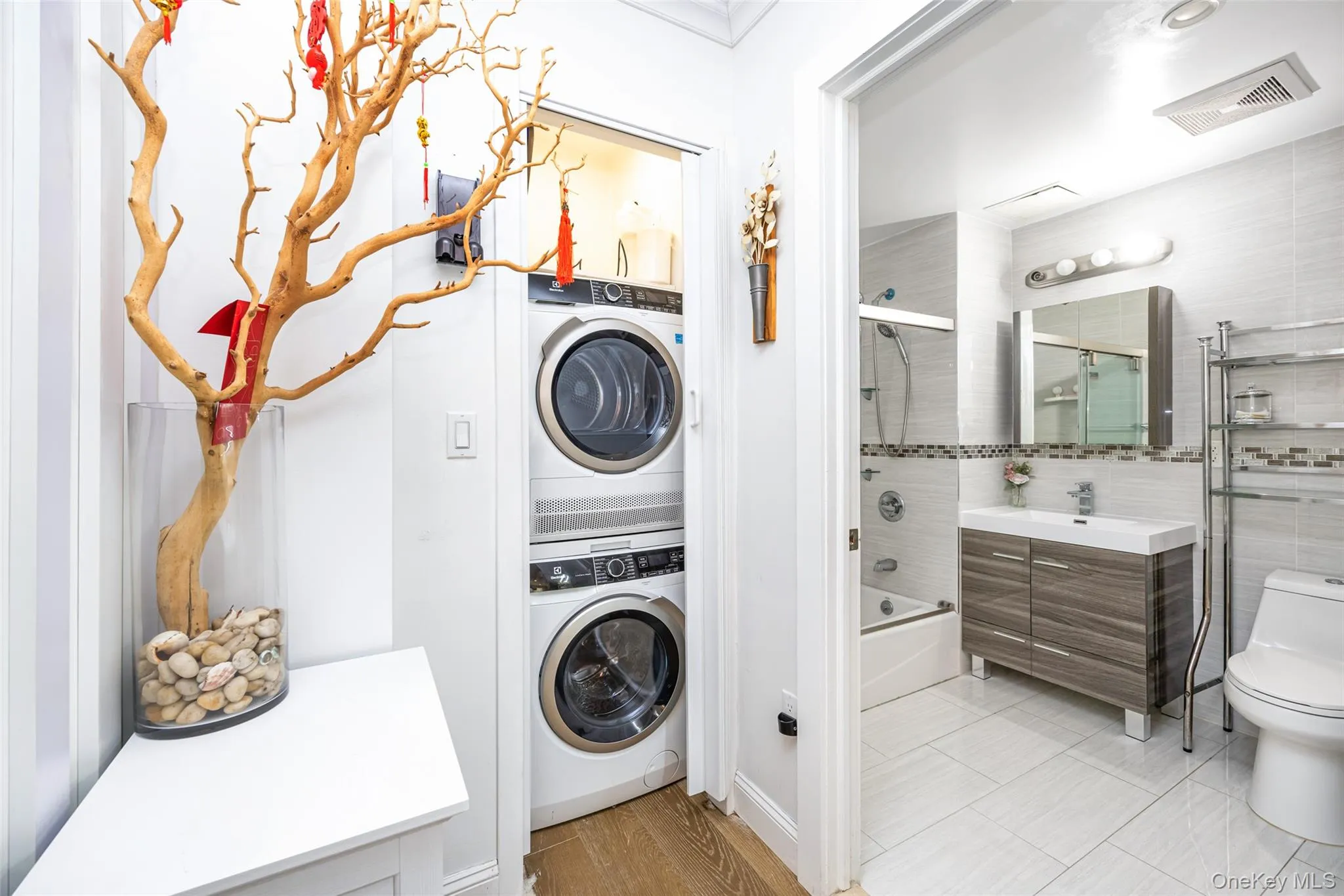 Laundry room with stacked washing machine and dryer and light wood-type flooring Laundry room with stacked washing machine and dryer and light wood-type flooring