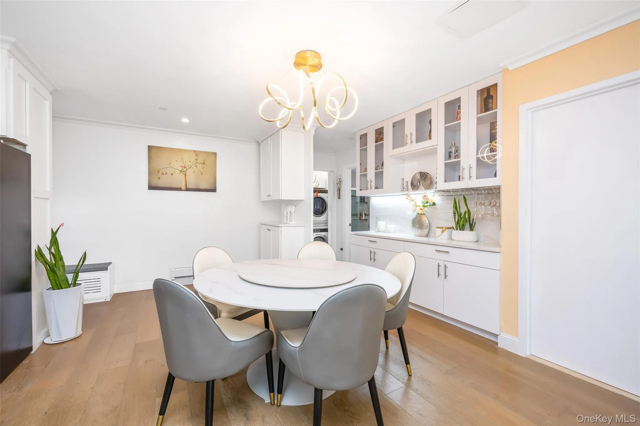 Dining room with stacked washer and clothes dryer, light wood-style floors, a chandelier, crown molding, and recessed lighting Dining room with stacked washer and clothes dryer, light wood-style floors, a chandelier, crown molding, and recessed lighting