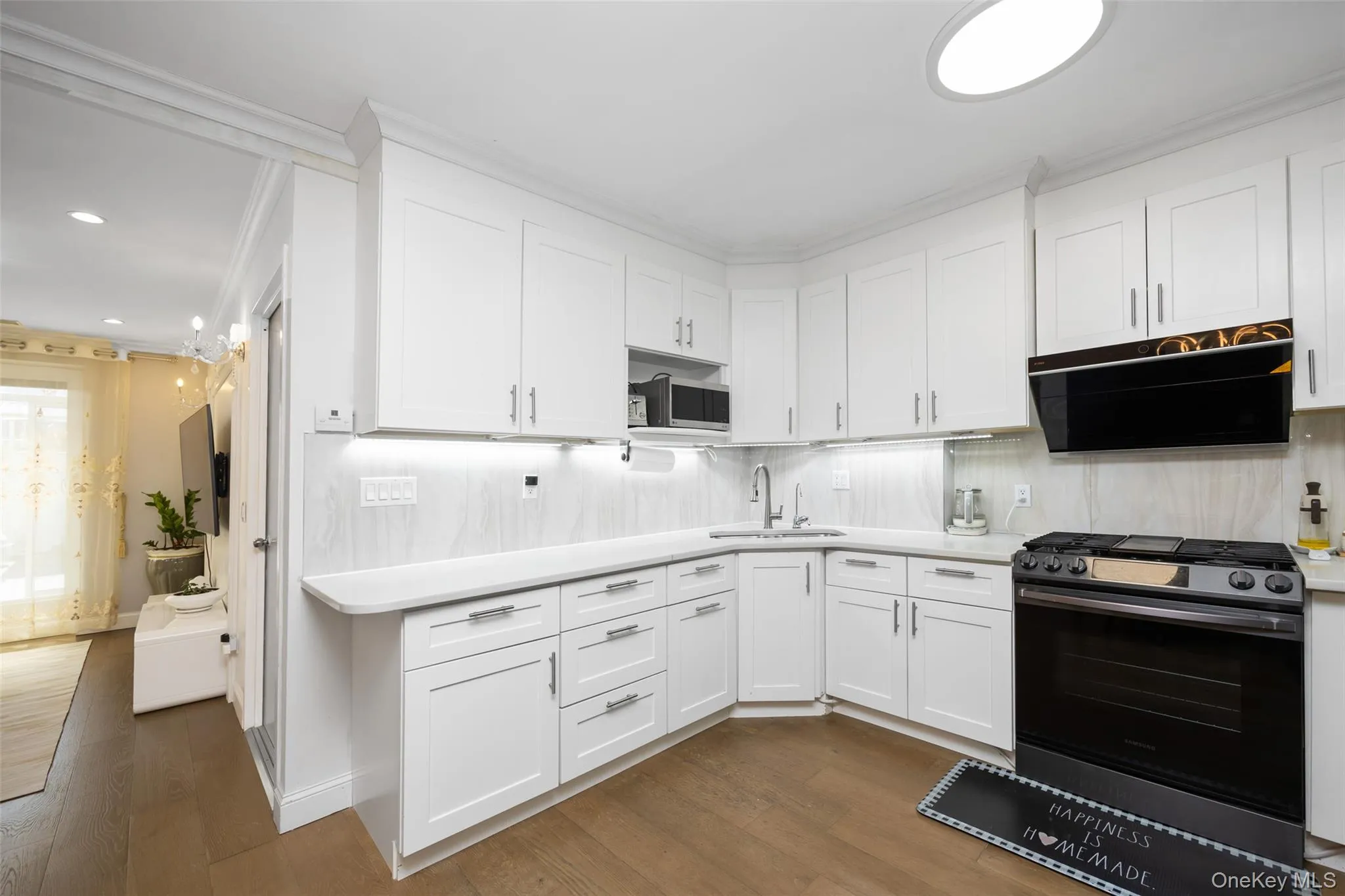Kitchen featuring stainless steel appliances, white cabinetry, dark wood-style floors, exhaust hood, and tasteful backsplash Kitchen featuring stainless steel appliances, white cabinetry, dark wood-style floors, exhaust hood, and tasteful backsplash