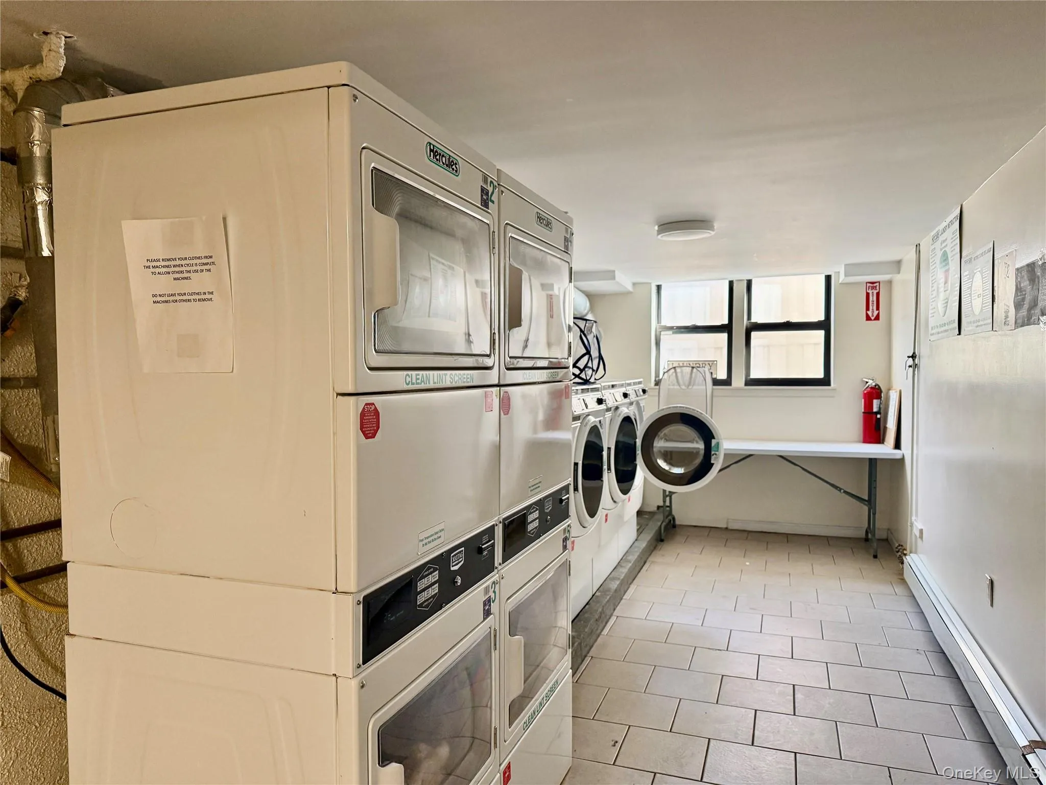 Communal laundry room featuring a baseboard radiator and estacked washer and dryer Communal laundry room featuring a baseboard radiator and estacked washer and dryer