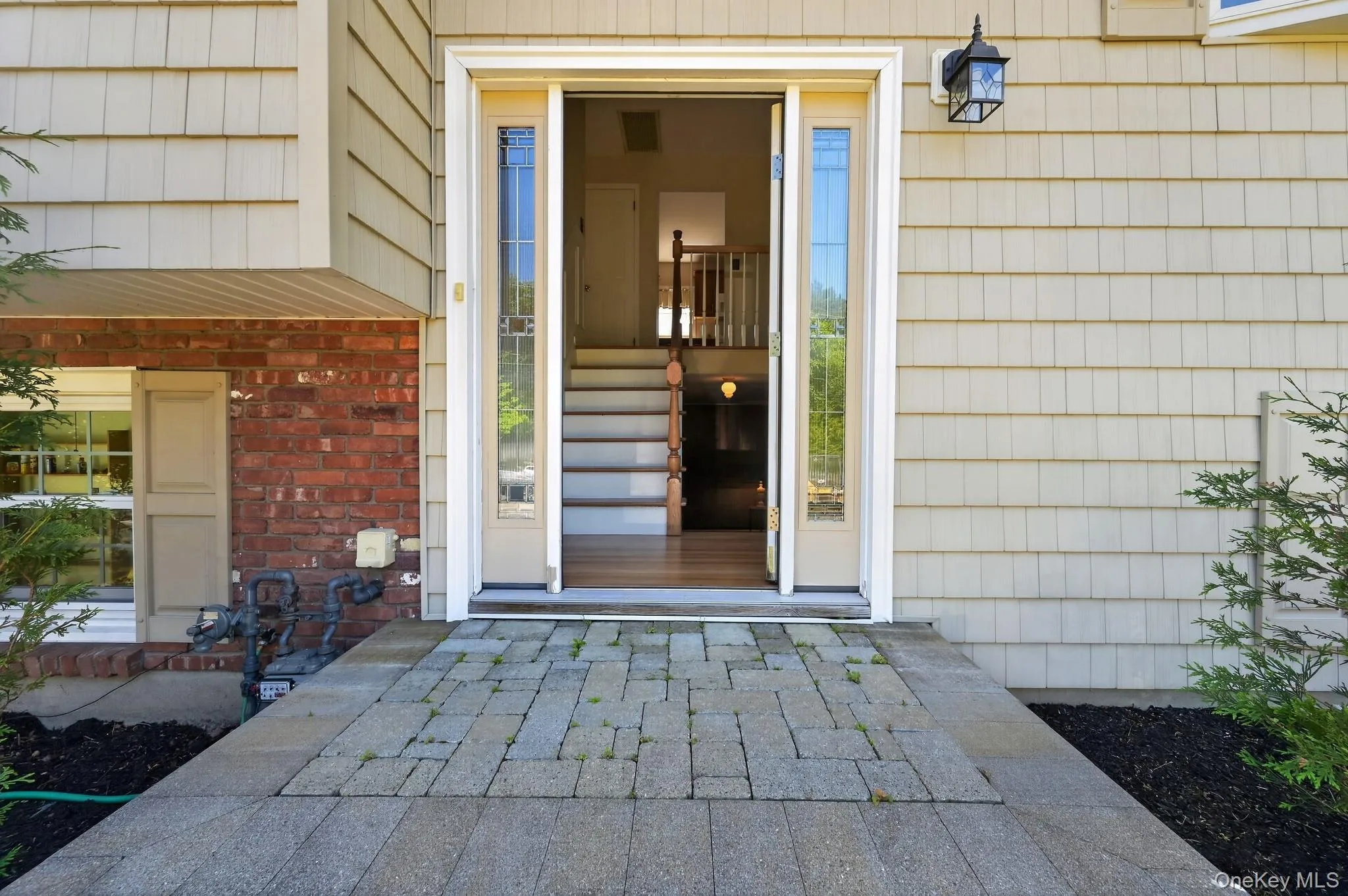 Entryway featuring a decorative transom, sidelight windows, and a stone paver walkway Entryway featuring a decorative transom, sidelight windows, and a stone paver walkway