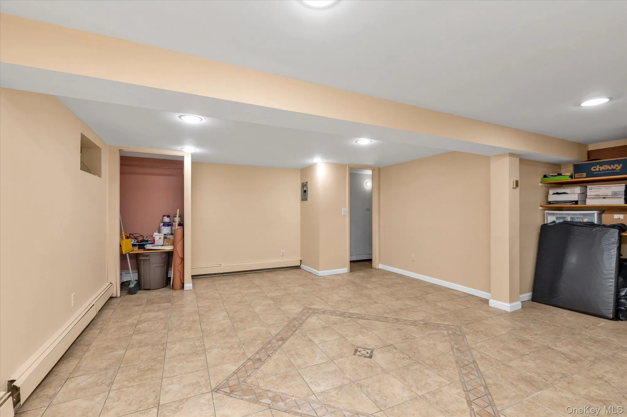 Spacious room featuring neutral tone walls, tile flooring with a decorative inlay, recessed lighting, and built-in shelving Spacious room featuring neutral tone walls, tile flooring with a decorative inlay, recessed lighting, and built-in shelving