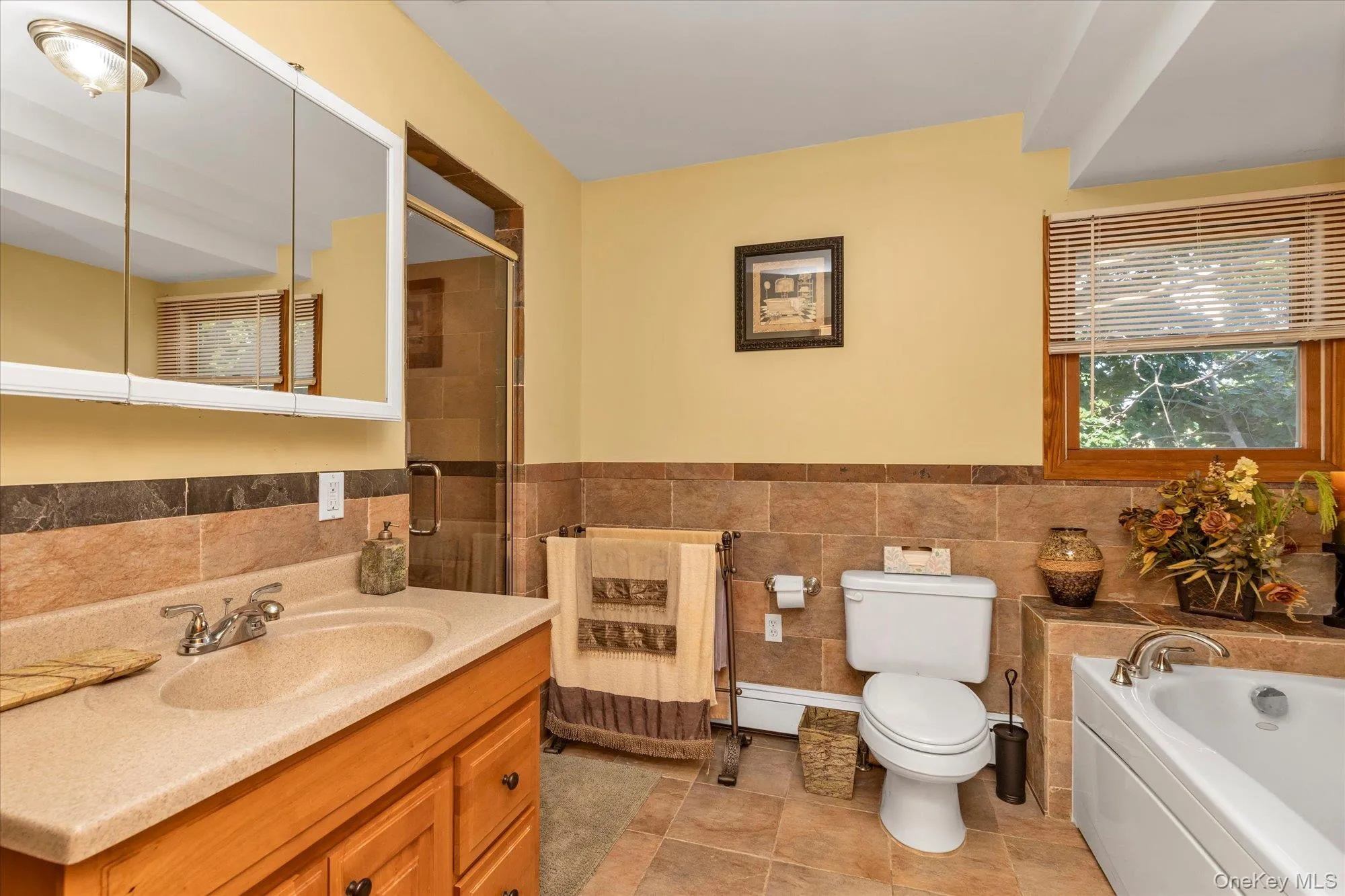 Bathroom featuring an integrated vanity sink with storage cabinetry, a framed shower with a clear glass door, and a built-in tub Bathroom featuring an integrated vanity sink with storage cabinetry, a framed shower with a clear glass door, and a built-in tub
