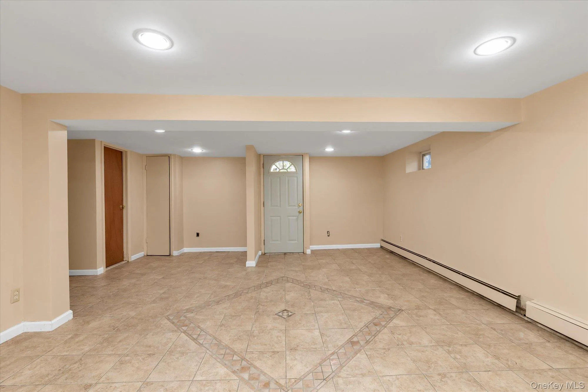 Spacious interior room featuring tile flooring with a decorative inlay, recessed ceiling lighting, a window, and baseboard heating Spacious interior room featuring tile flooring with a decorative inlay, recessed ceiling lighting, a window, and baseboard heating
