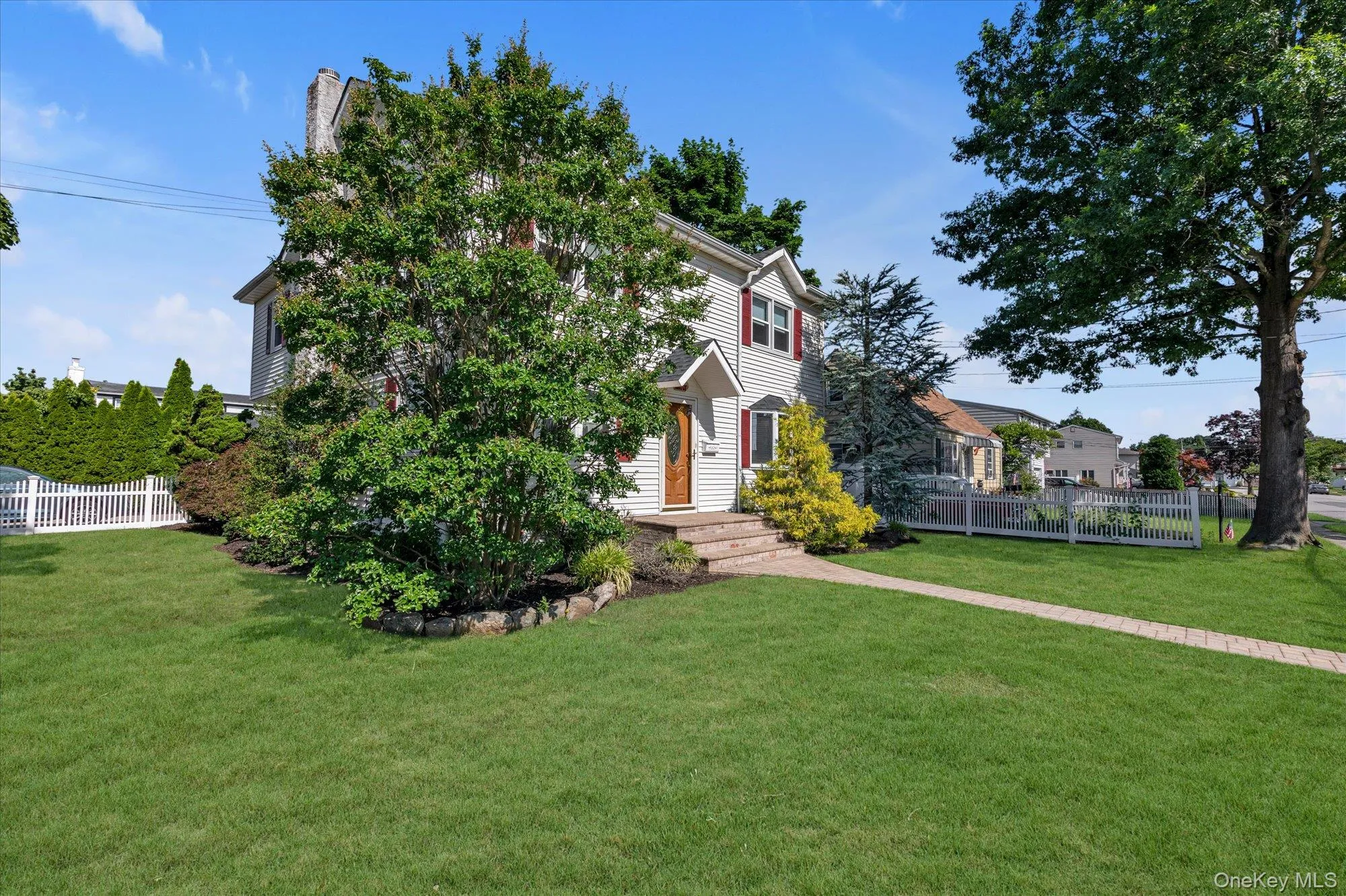 Traditional two-story residence featuring light siding, red shutters, and a prominent front entry with a wood door Traditional two-story residence featuring light siding, red shutters, and a prominent front entry with a wood door