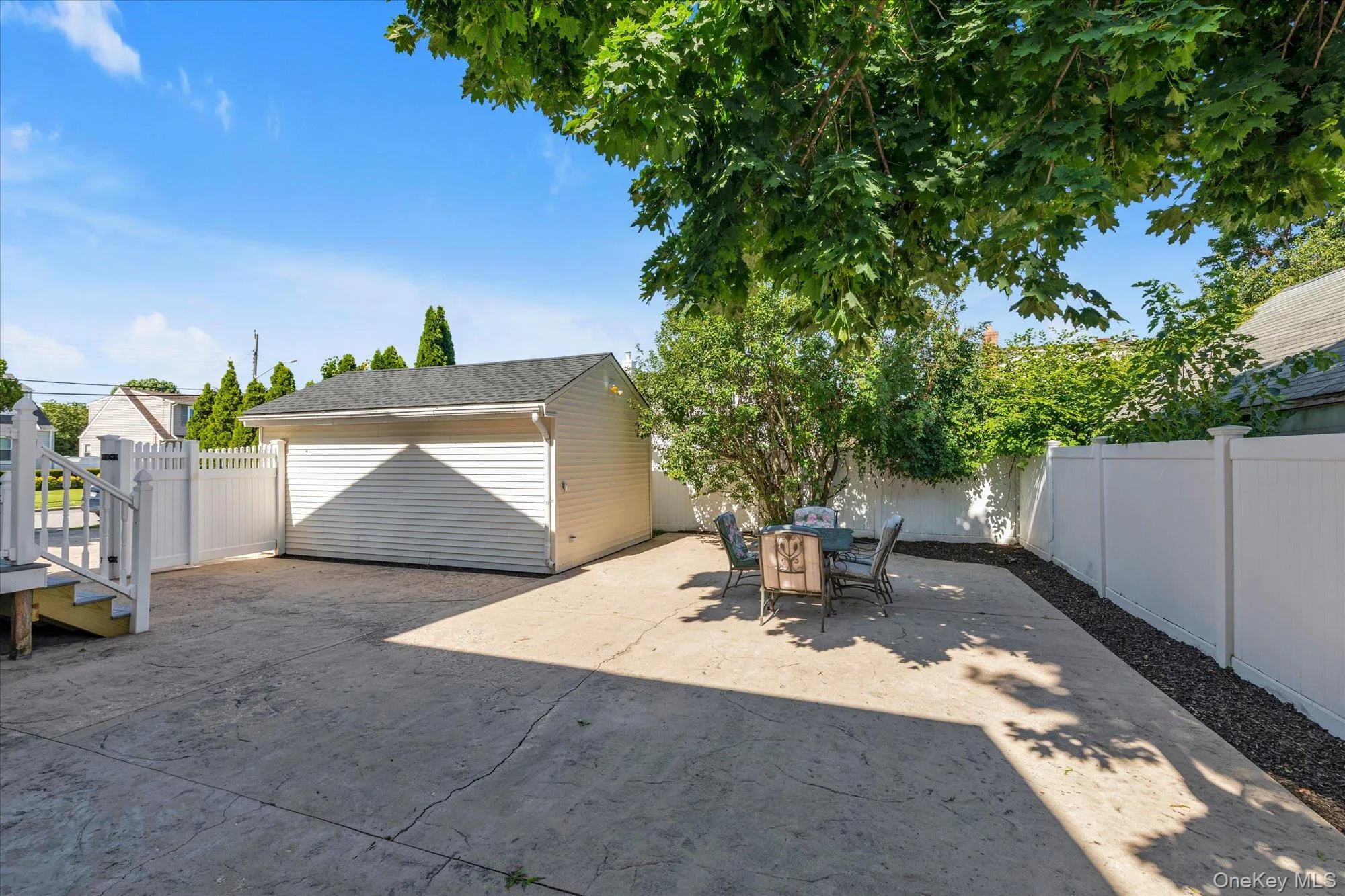 Spacious outdoor patio with stamped concrete, surrounded by a white privacy fence Spacious outdoor patio with stamped concrete, surrounded by a white privacy fence