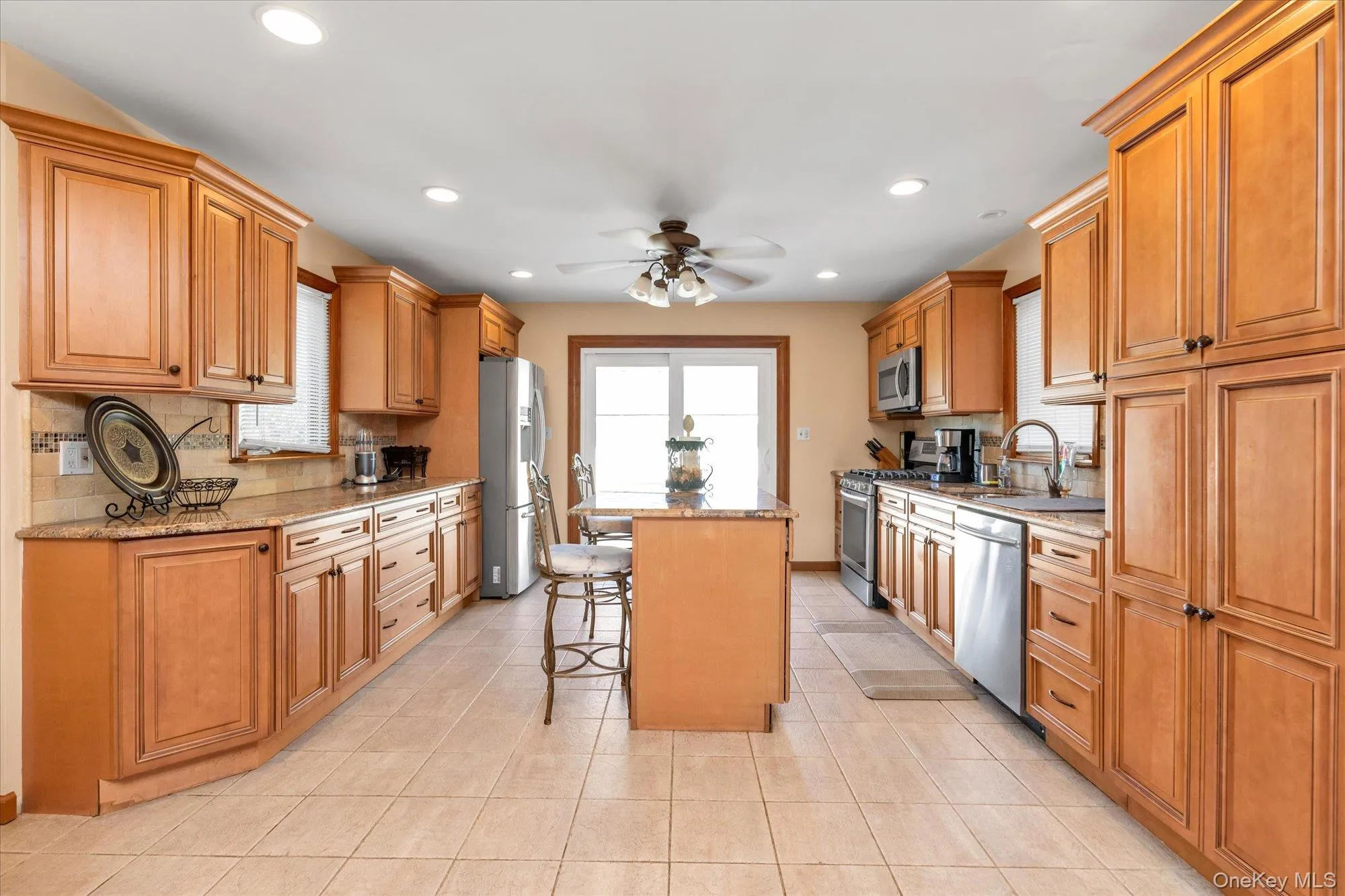 Expansive kitchen featuring light wood cabinetry, stone countertops, stainless steel appliances, recessed lighting, and tile flooring Expansive kitchen featuring light wood cabinetry, stone countertops, stainless steel appliances, recessed lighting, and tile flooring