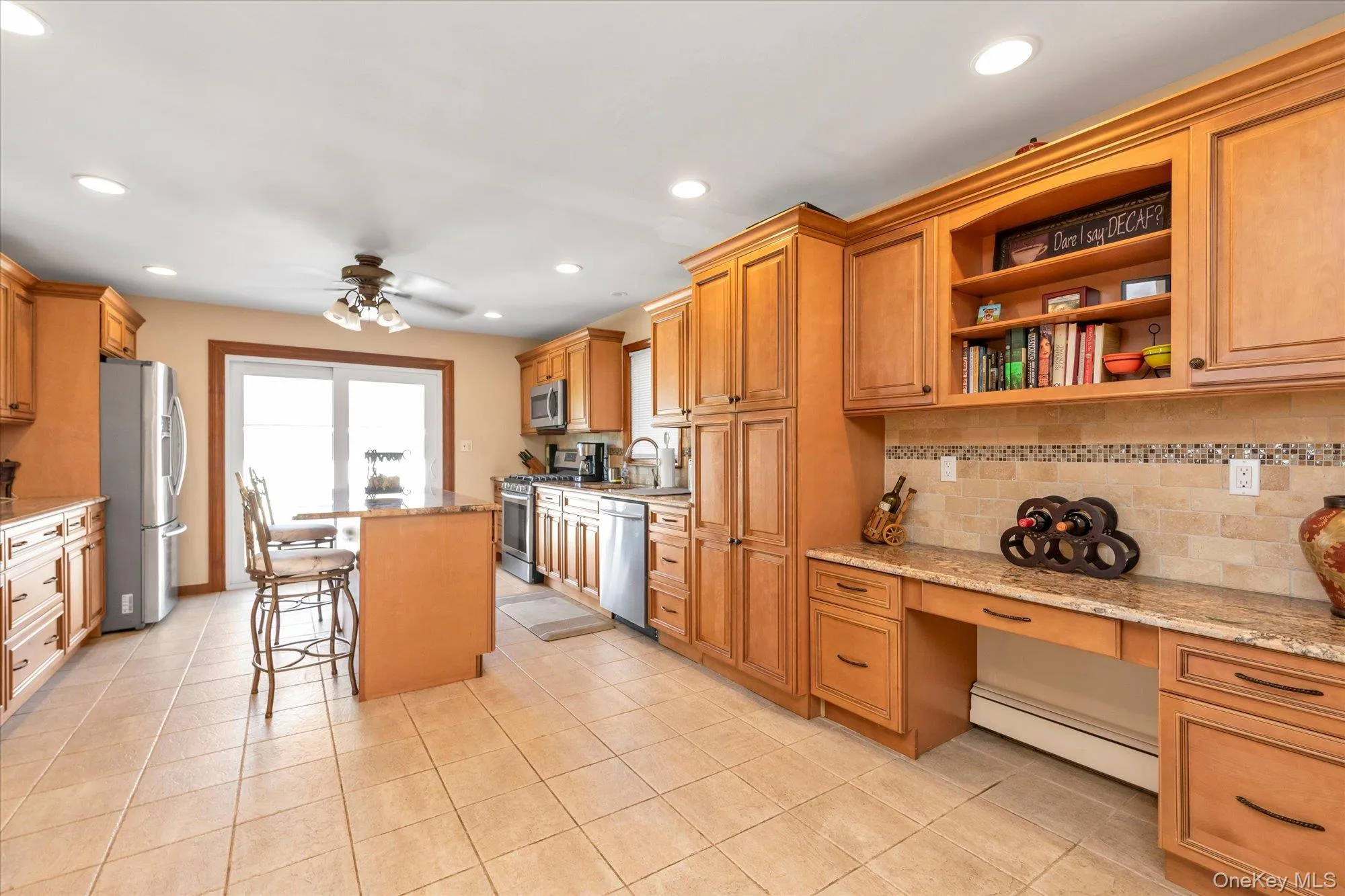 Spacious kitchen featuring extensive wood cabinetry, granite countertops, stainless steel appliances, a tiled backsplash, and recessed lighting Spacious kitchen featuring extensive wood cabinetry, granite countertops, stainless steel appliances, a tiled backsplash, and recessed lighting