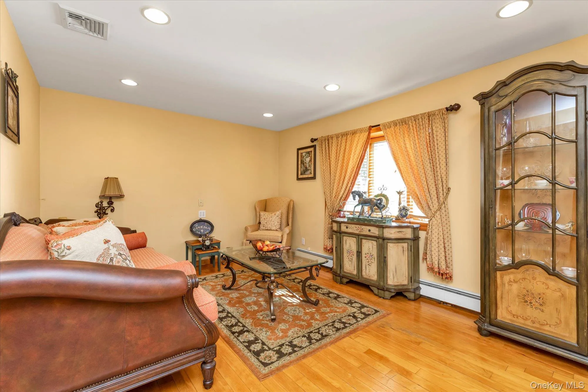 Living area featuring hardwood flooring, recessed lighting, a wooden staircase, and a doorway Living area featuring hardwood flooring, recessed lighting, a wooden staircase, and a doorway