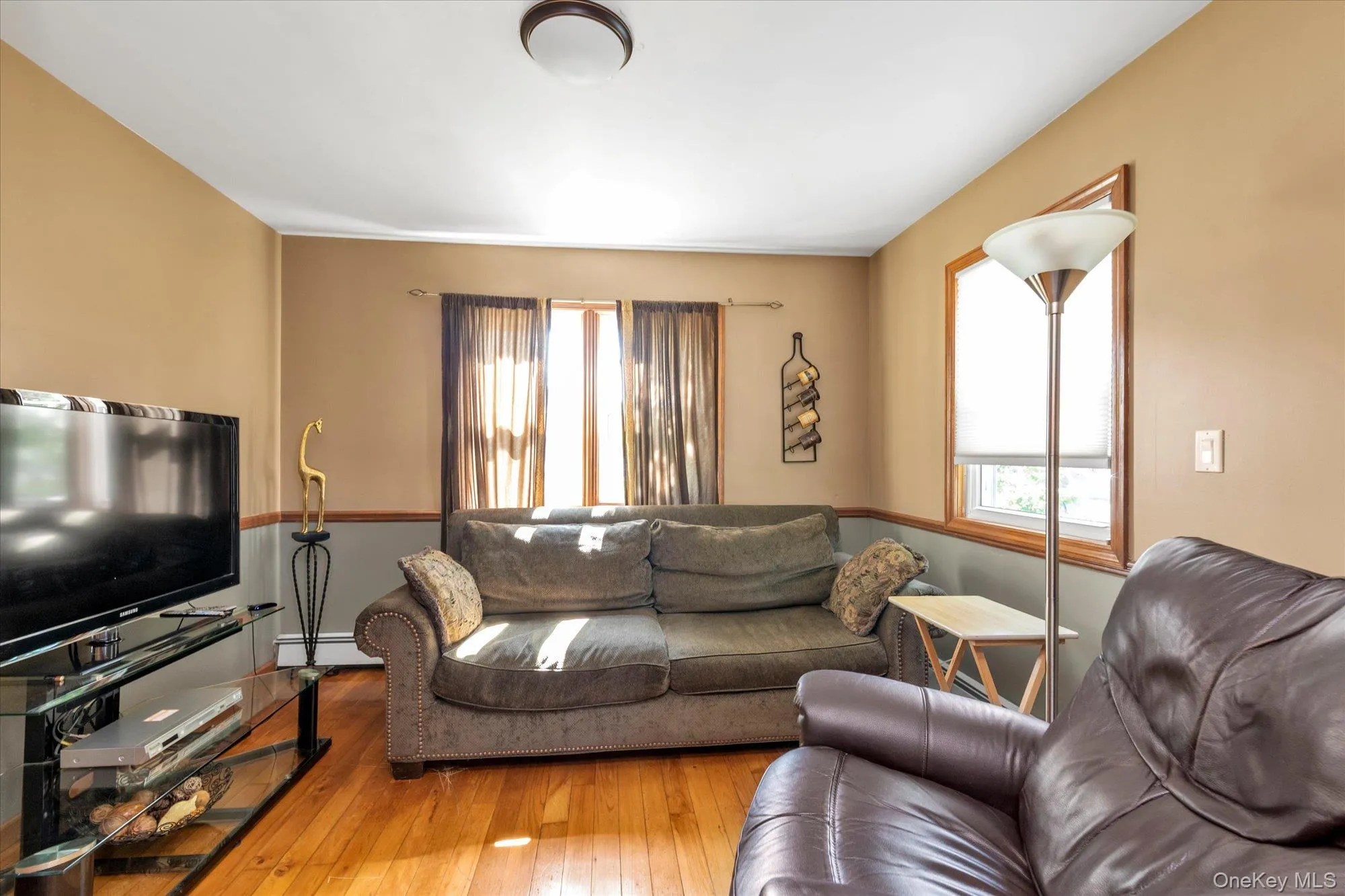 Living area featuring wood-finish flooring, a two-tone wall treatment, and multiple windows Living area featuring wood-finish flooring, a two-tone wall treatment, and multiple windows
