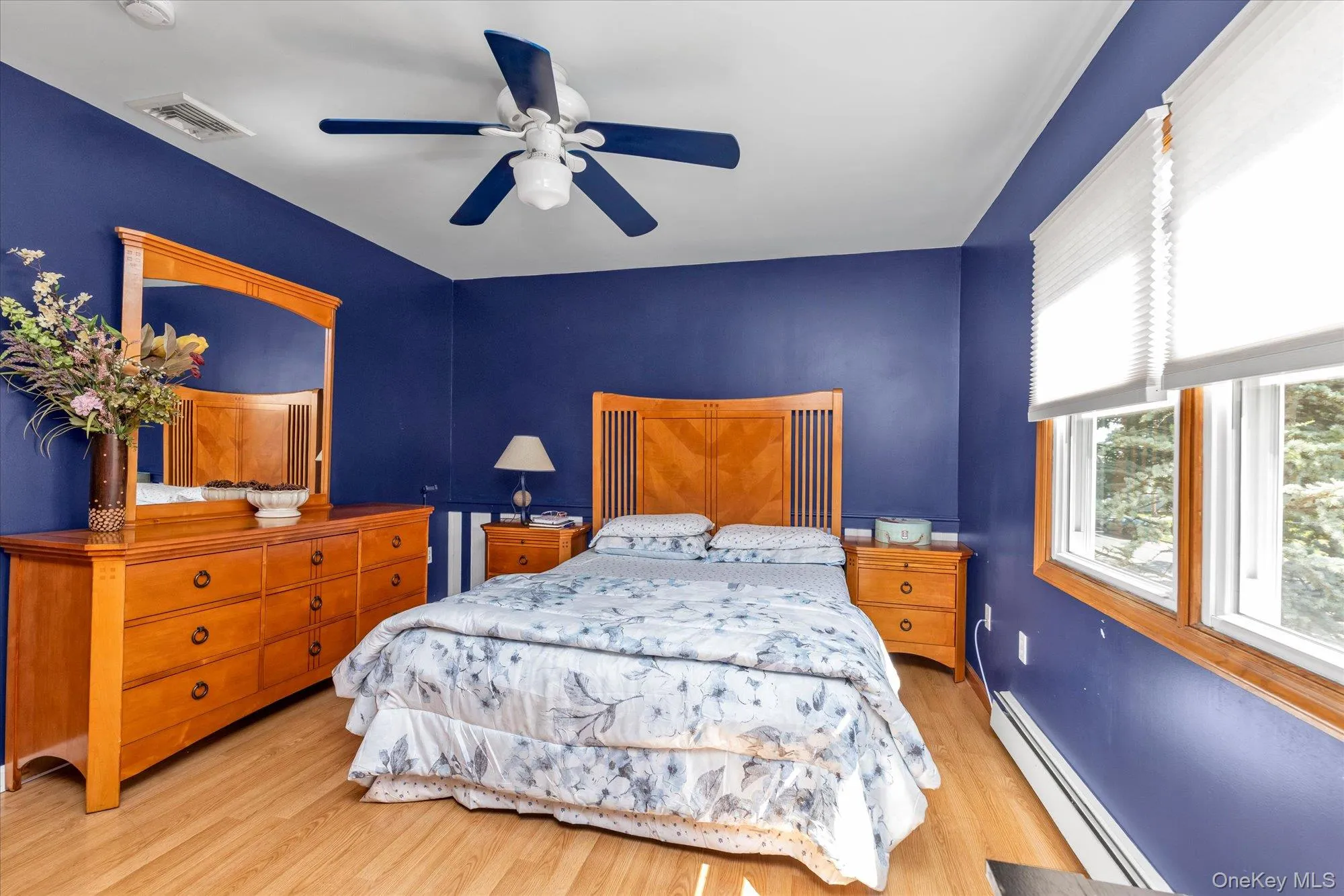 Room featuring wood-finish flooring, a ceiling fan with integrated lighting, and multiple windows Room featuring wood-finish flooring, a ceiling fan with integrated lighting, and multiple windows