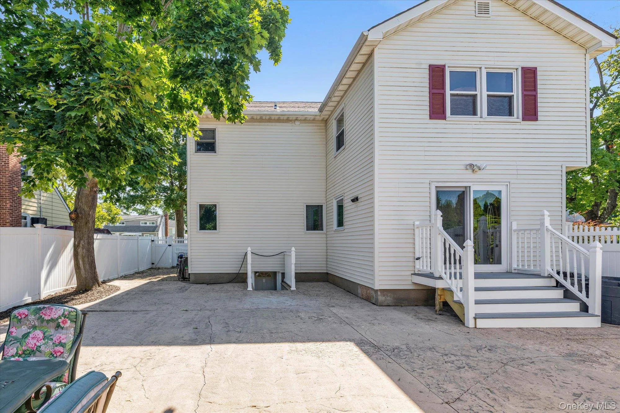 Expansive stamped concrete patio with direct access to the property via sliding glass doors and a white-railed deck Expansive stamped concrete patio with direct access to the property via sliding glass doors and a white-railed deck