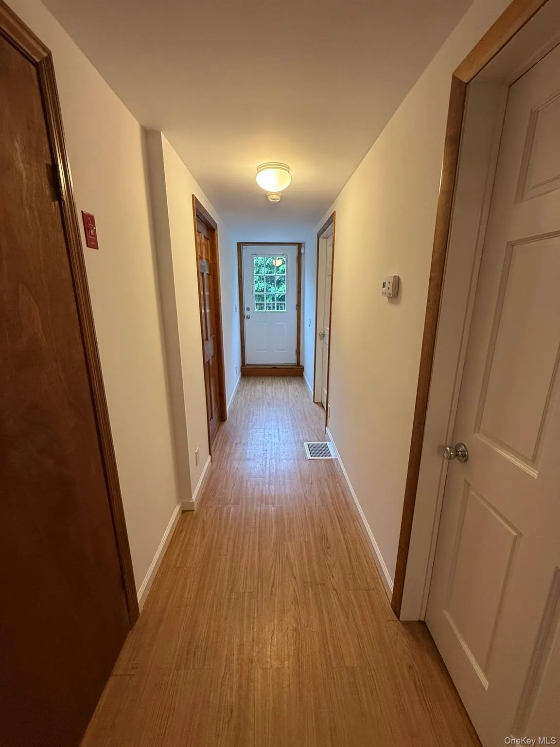 Hallway with laundry room and primary bedroom on the left and 2 bedrooms on the right. Leading to the back door to access the deck Hallway with laundry room and primary bedroom on the left and 2 bedrooms on the right. Leading to the back door to access the deck