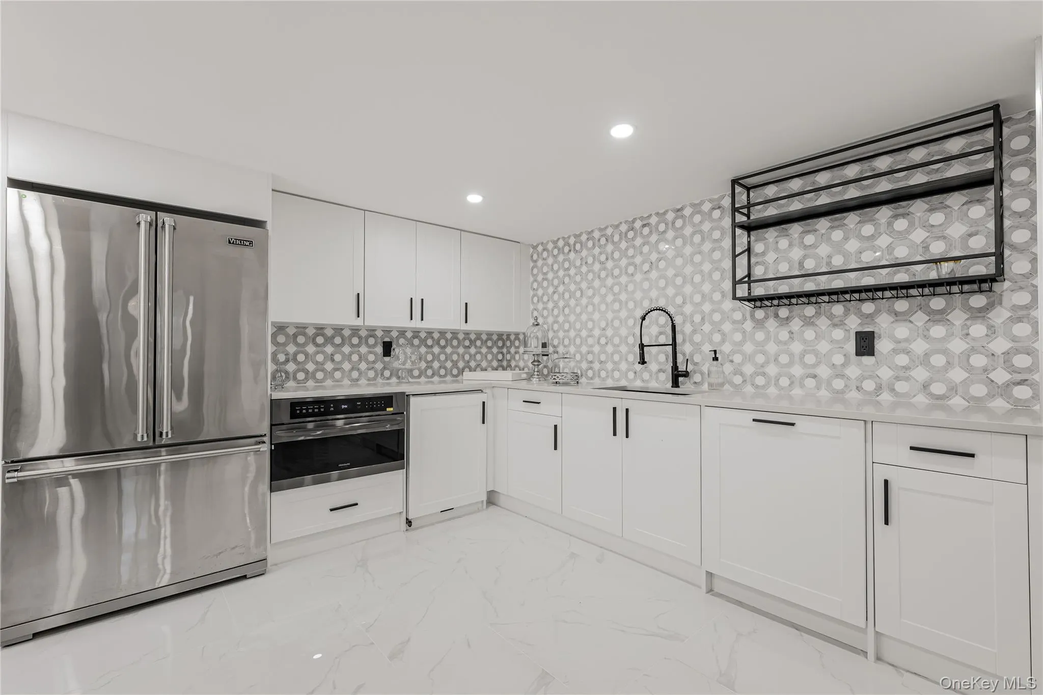 Kitchen with appliances with stainless steel finishes, light countertops, white cabinets, light marble finish flooring, and backsplash Kitchen with appliances with stainless steel finishes, light countertops, white cabinets, light marble finish flooring, and backsplash