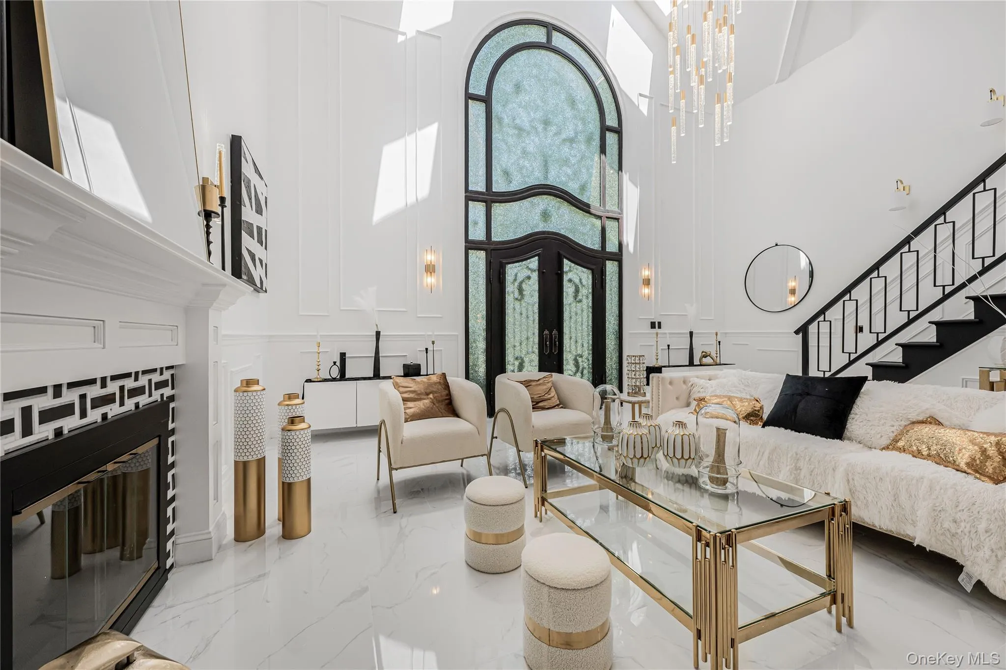 Living area with a towering ceiling, a decorative wall, stairs, marble tiled floors, and a fireplace Living area with a towering ceiling, a decorative wall, stairs, marble tiled floors, and a fireplace