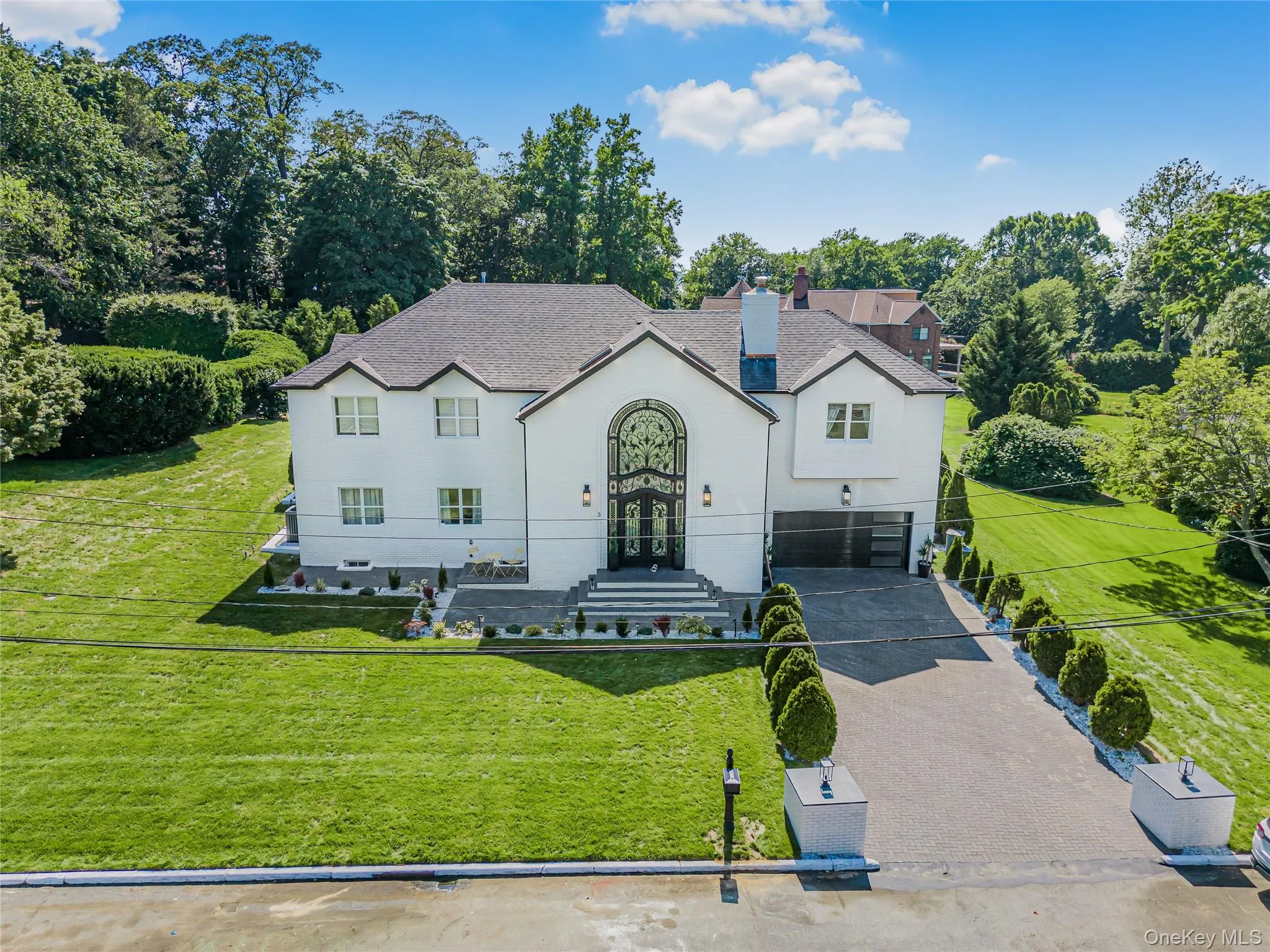 Traditional-style house featuring asphalt driveway, a garage, a front yard, stucco siding, and french doors Traditional-style house featuring asphalt driveway, a garage, a front yard, stucco siding, and french doors