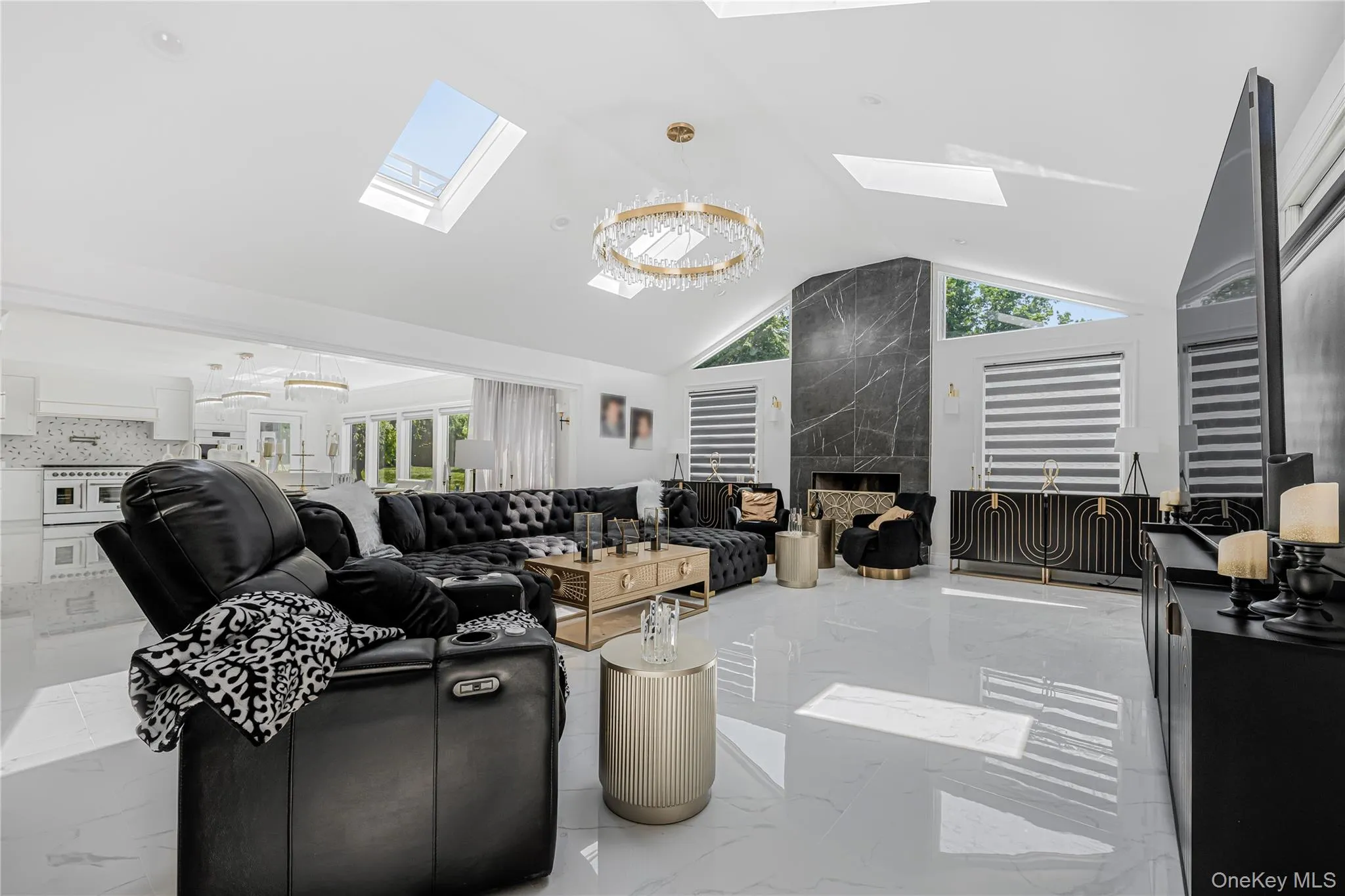 Living room with a skylight, vaulted ceiling, marble tiled flooring, and a premium fireplace Living room with a skylight, vaulted ceiling, marble tiled flooring, and a premium fireplace