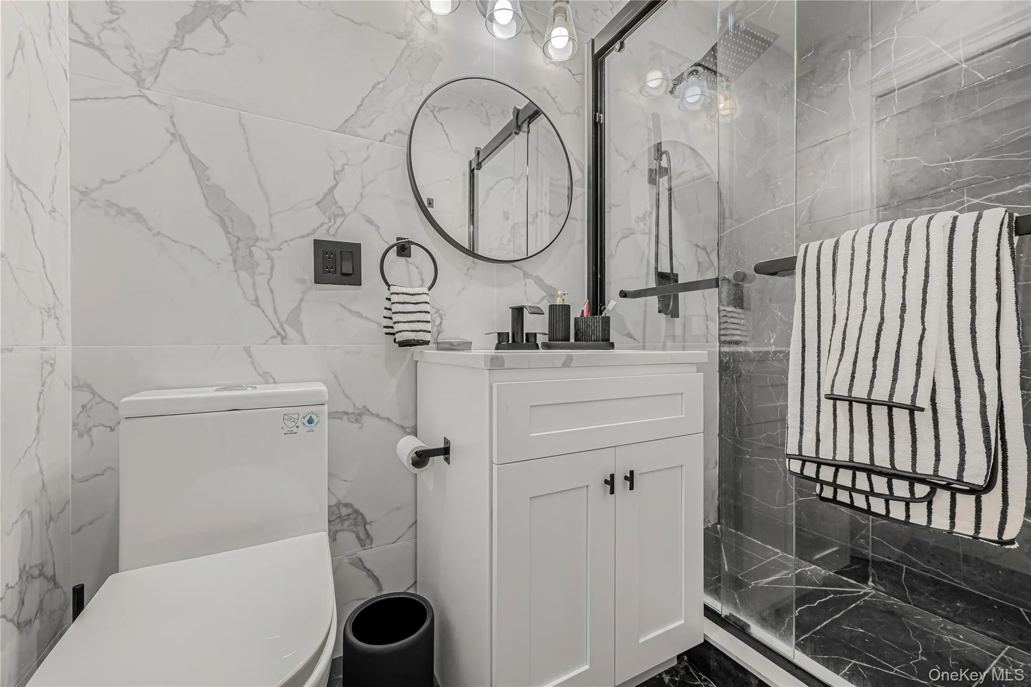 Full bath featuring tile walls, vanity, a marble finish shower, and marble finish floors Full bath featuring tile walls, vanity, a marble finish shower, and marble finish floors