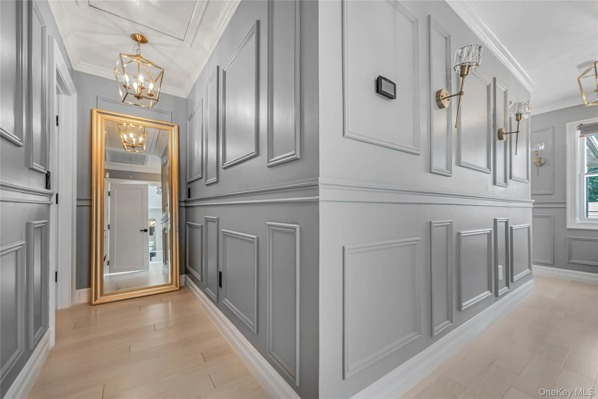 Hallway with a decorative wall, crown molding, and a chandelier Hallway with a decorative wall, crown molding, and a chandelier