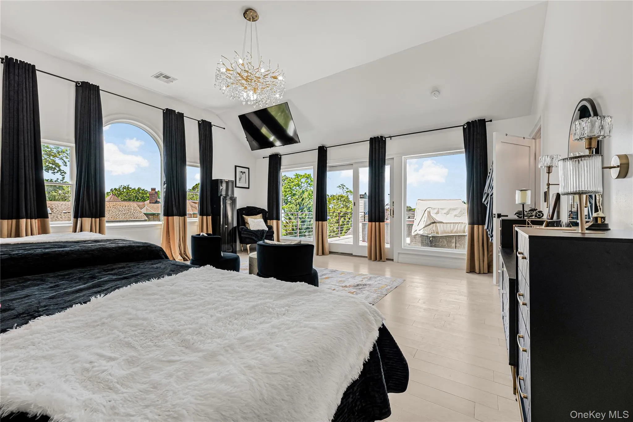 Bedroom featuring lofted ceiling, access to exterior, multiple windows, light wood-type flooring, and a chandelier Bedroom featuring lofted ceiling, access to exterior, multiple windows, light wood-type flooring, and a chandelier