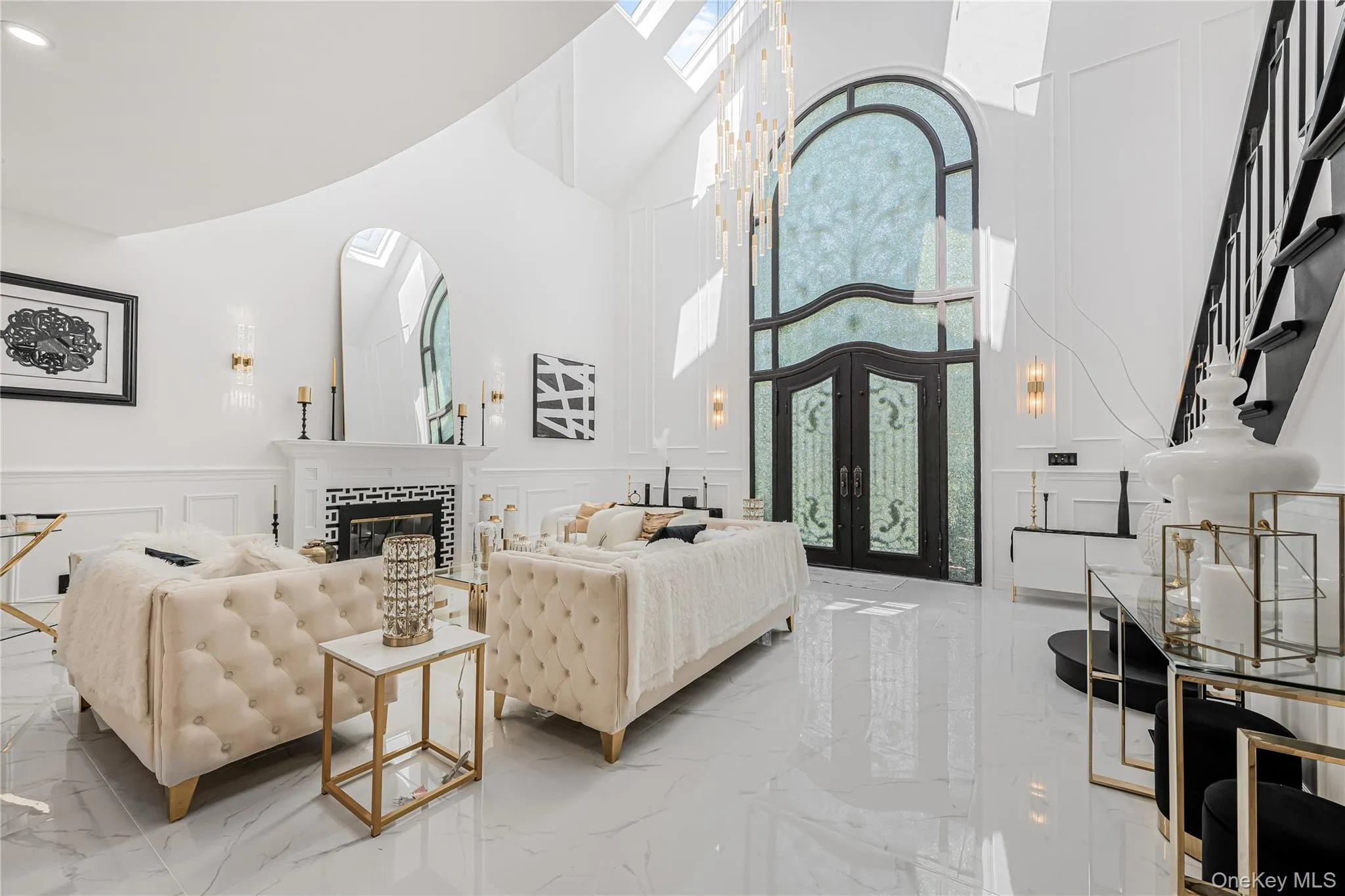 Living room featuring a decorative wall, light marble finish floors, a high ceiling, french doors, and a wainscoted wall Living room featuring a decorative wall, light marble finish floors, a high ceiling, french doors, and a wainscoted wall