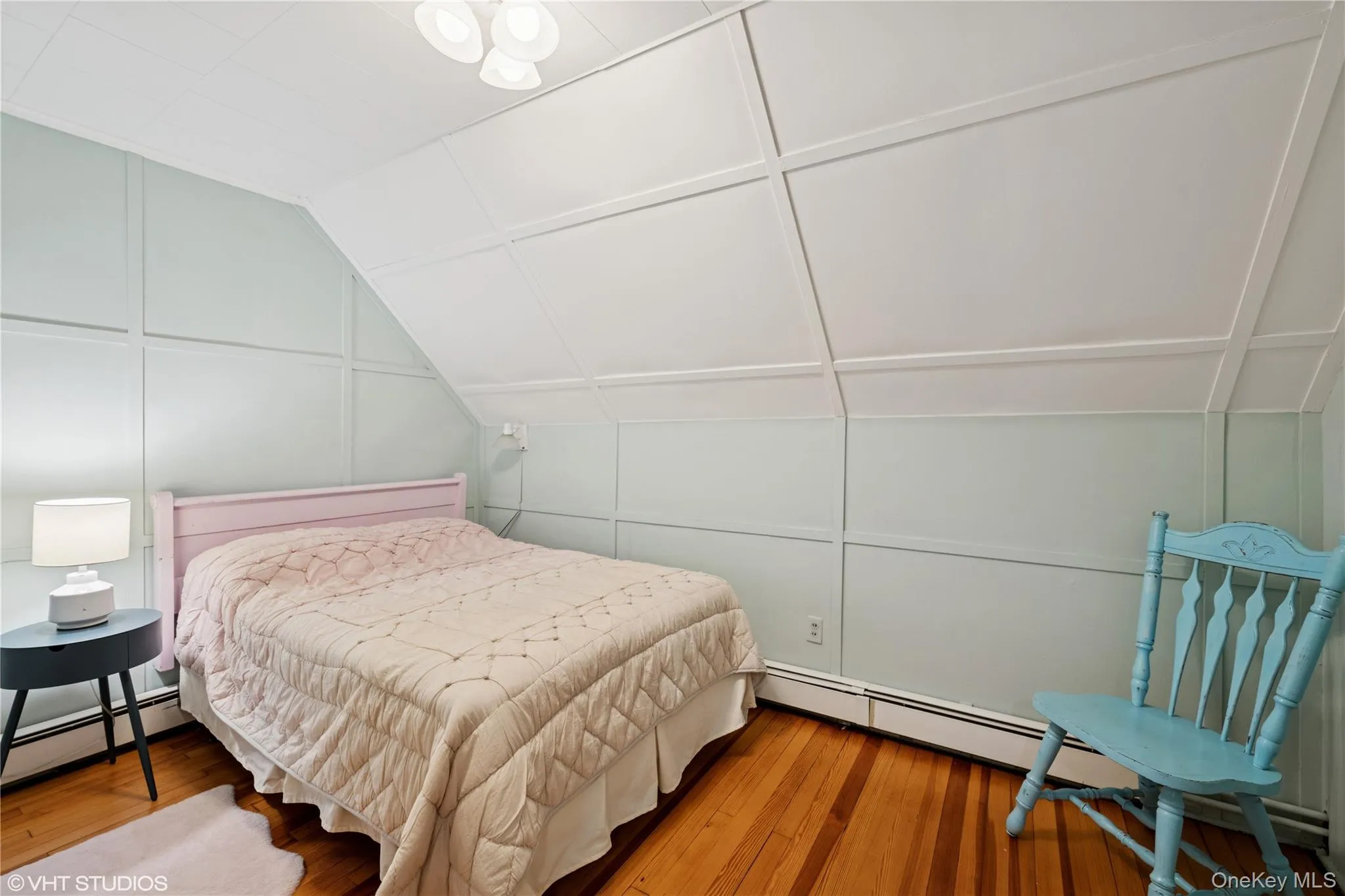 Bedroom featuring lofted ceiling, hardwood / wood-style floors, a decorative wall, and a baseboard heating unit Bedroom featuring lofted ceiling, hardwood / wood-style floors, a decorative wall, and a baseboard heating unit