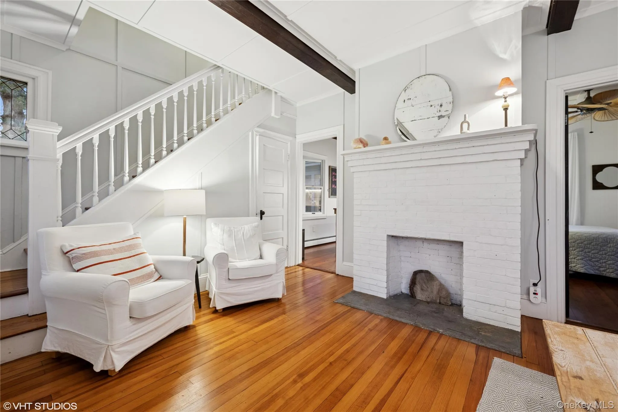 Living area with hardwood / wood-style floors, stairs, beam ceiling, and a fireplace Living area with hardwood / wood-style floors, stairs, beam ceiling, and a fireplace