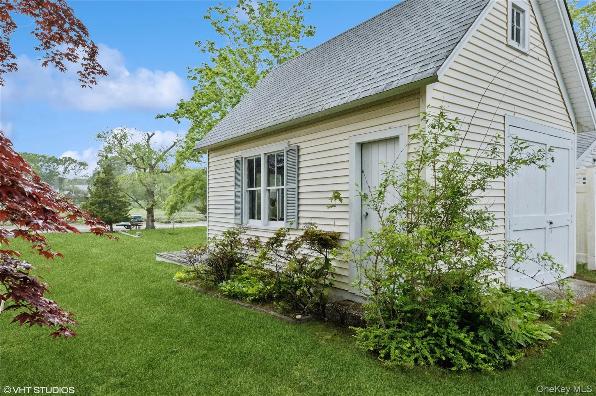 View of side of home featuring a lawn and a shingled roof View of side of home featuring a lawn and a shingled roof