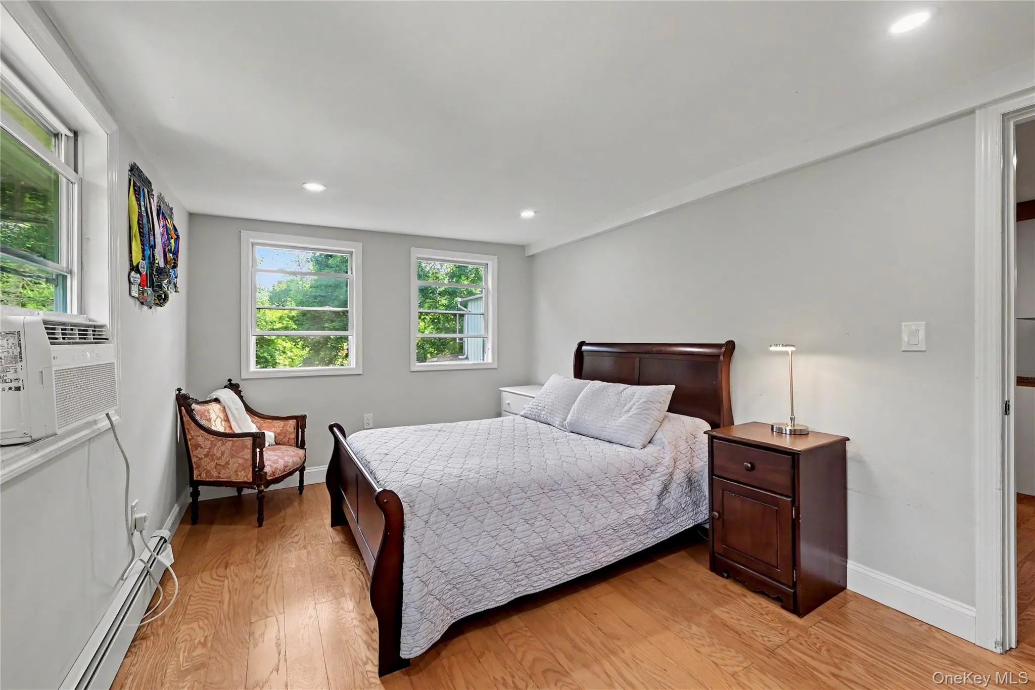Hardwood-style flooring throughout the primary bedroom with recessed lighting and natural lighting. Hardwood-style flooring throughout the primary bedroom with recessed lighting and natural lighting.