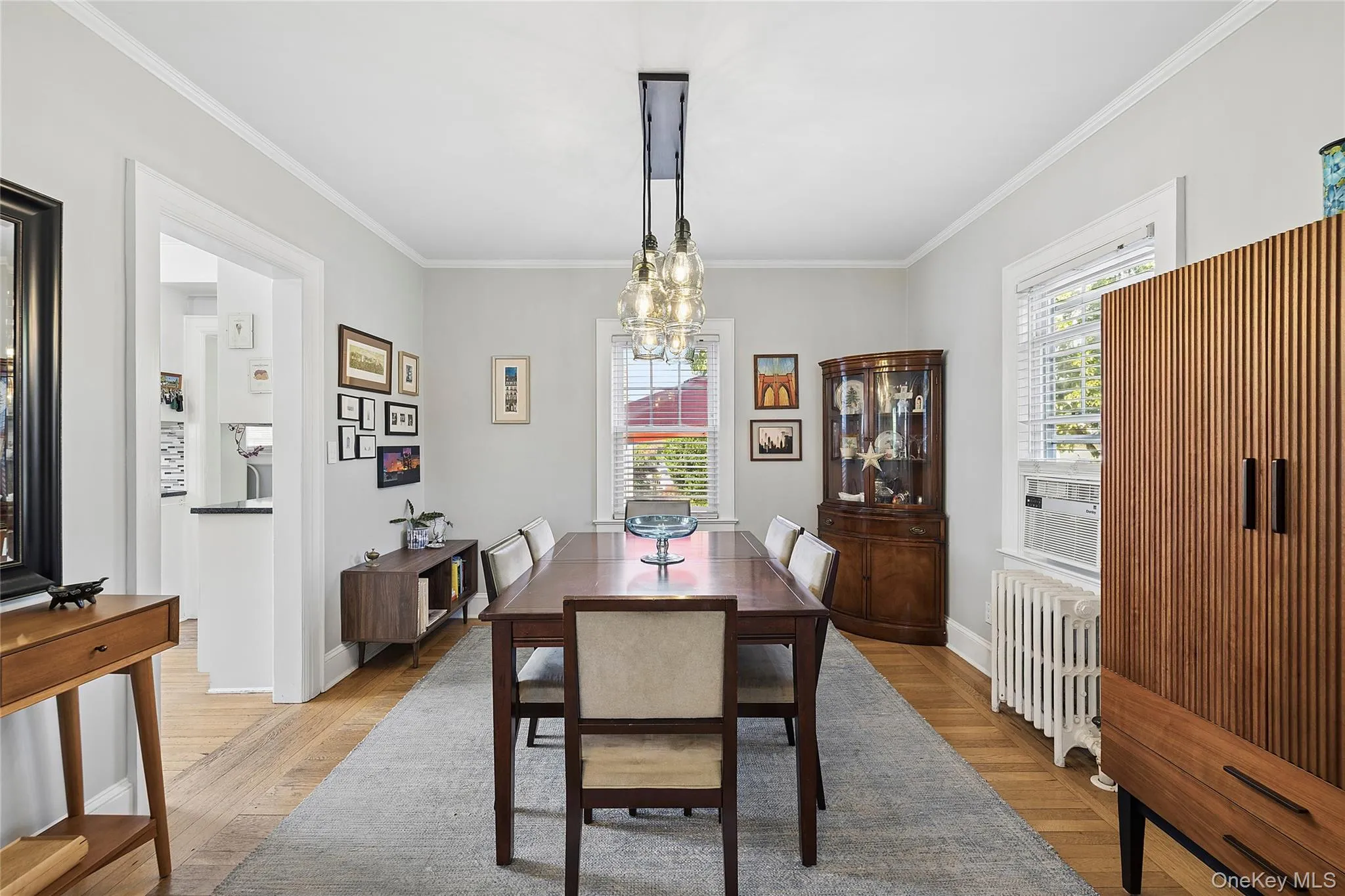 Dining area featuring wood-finish flooring, light gray wall paint, and white crown molding Dining area featuring wood-finish flooring, light gray wall paint, and white crown molding