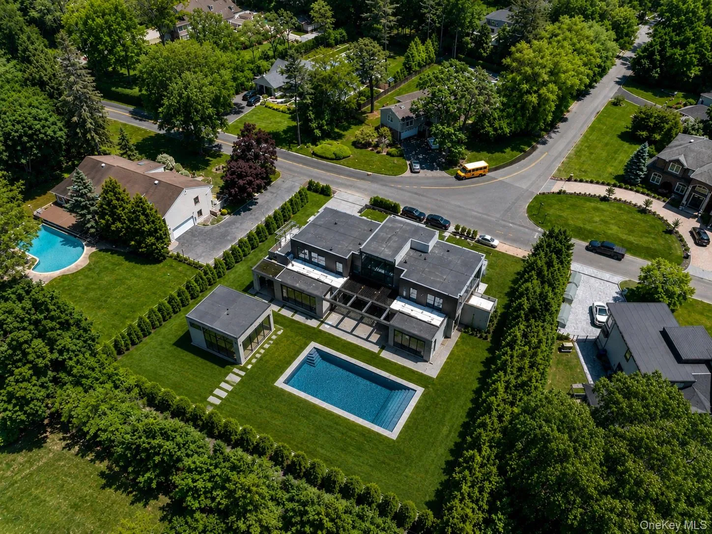 Modern residence featuring a rectangular swimming pool, manicured lawn, and mature perimeter landscaping Modern residence featuring a rectangular swimming pool, manicured lawn, and mature perimeter landscaping