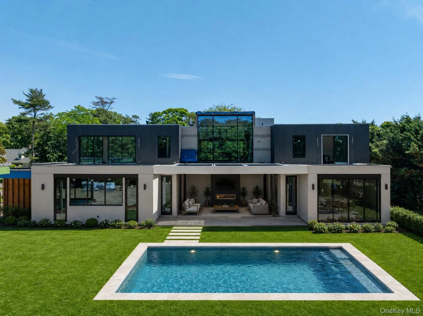 Modern exterior featuring a rectangular in-ground pool, expansive green lawn, and a spacious patio Modern exterior featuring a rectangular in-ground pool, expansive green lawn, and a spacious patio